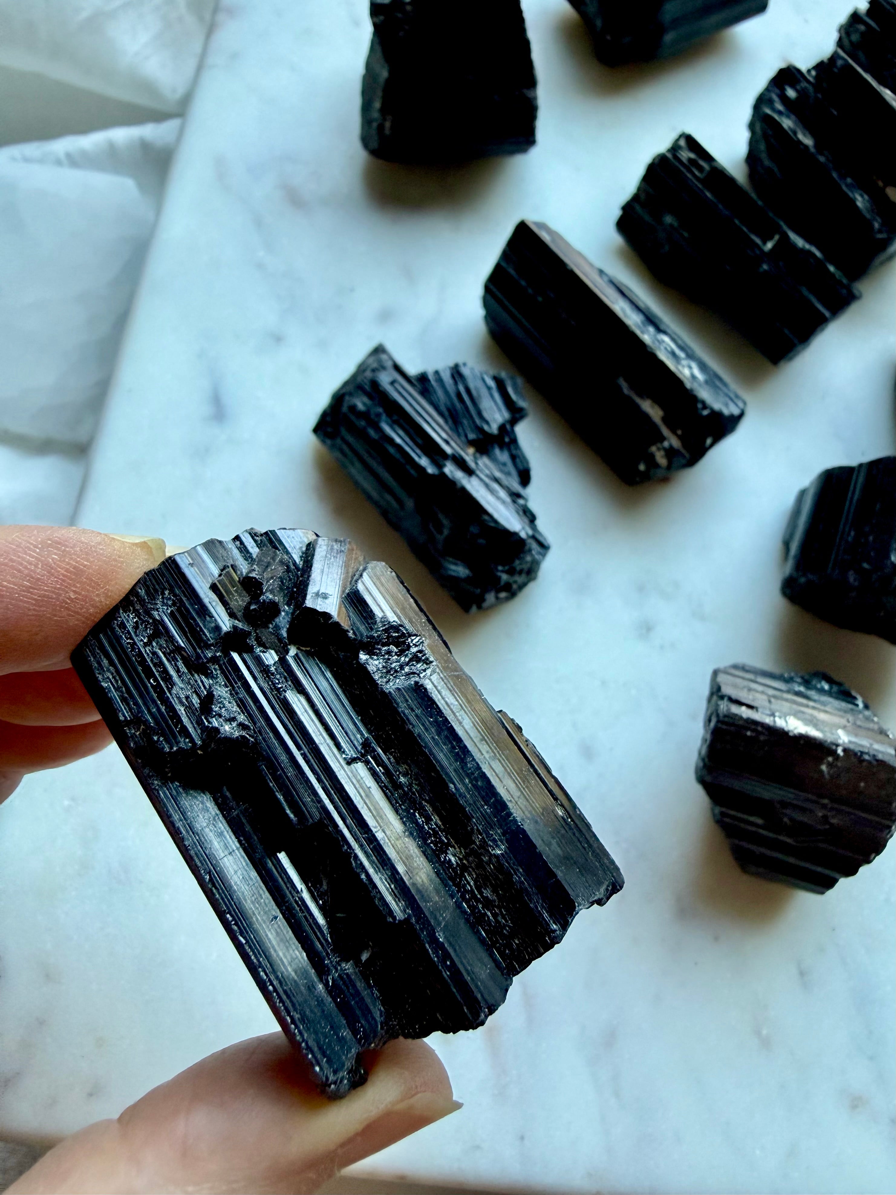 Natural Black Tourmaline chunks showing rough unpolished surfaces, glossy striations, and varied crystal growth