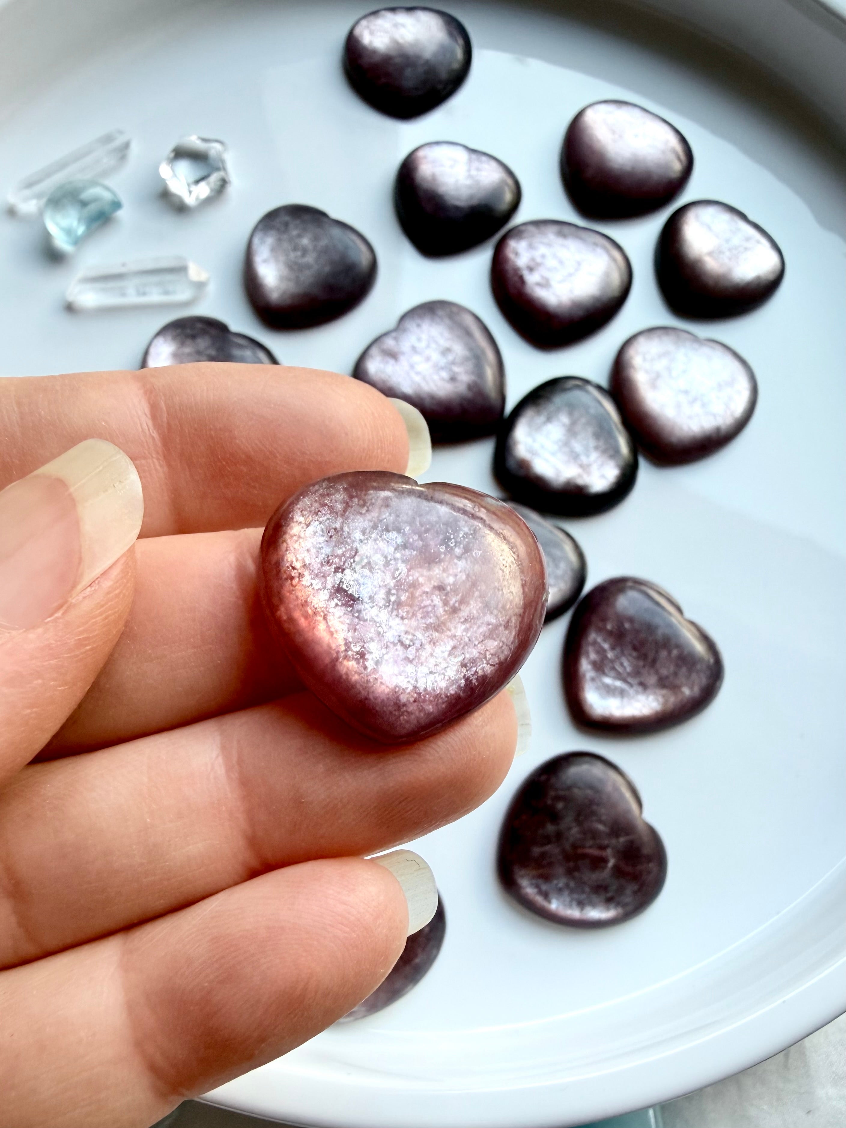 Small gem lepidolite crystal hearts grouped together showing natural purple tones and shimmer