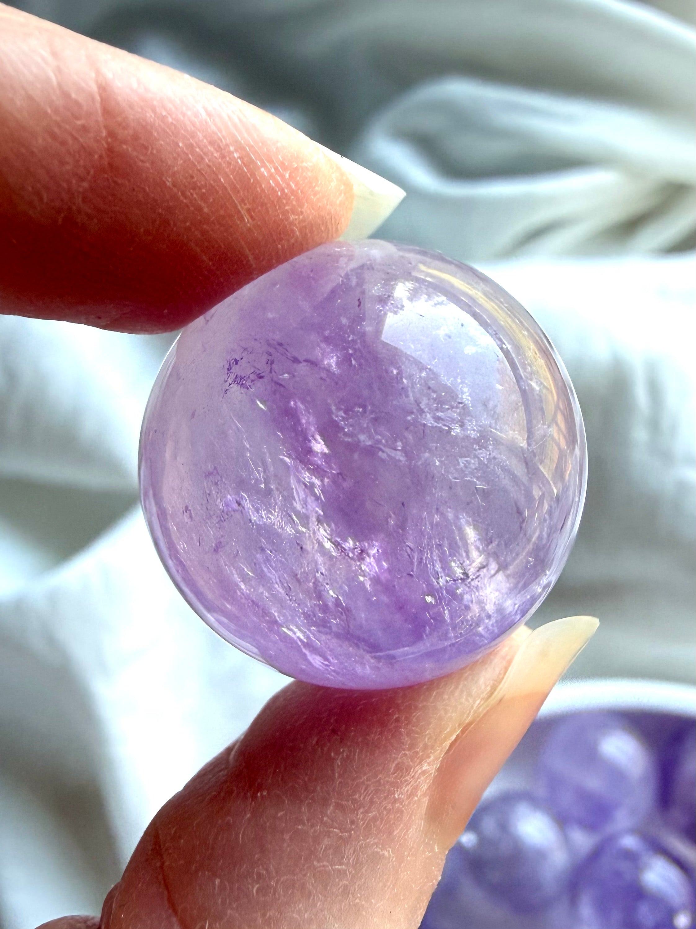 small smoky amethyst crystal sphere held in hand showing size and clarity