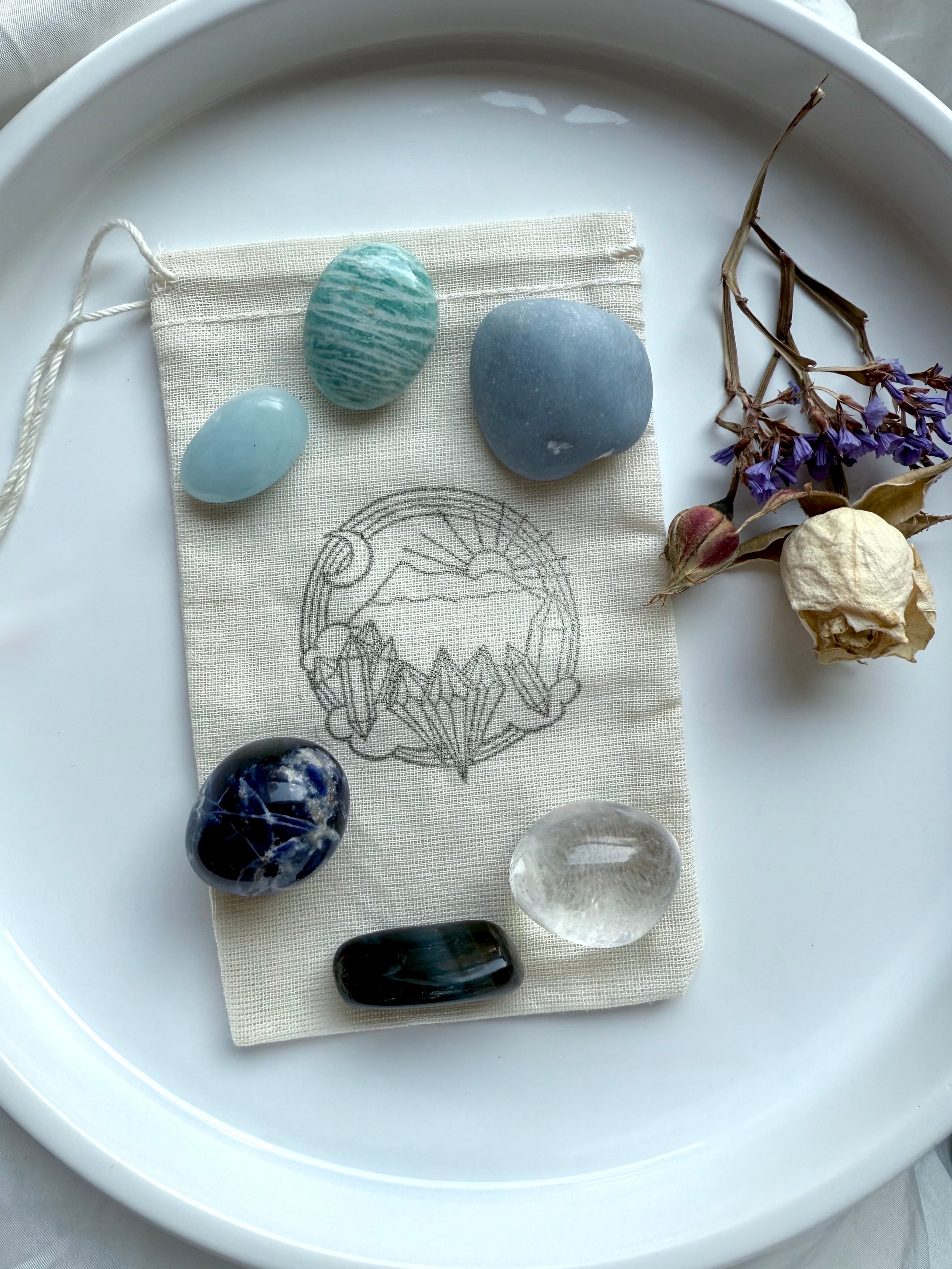 Throat Chakra Crystal Set displayed with cotton pouch and dried flowers — six stones for truth and expression