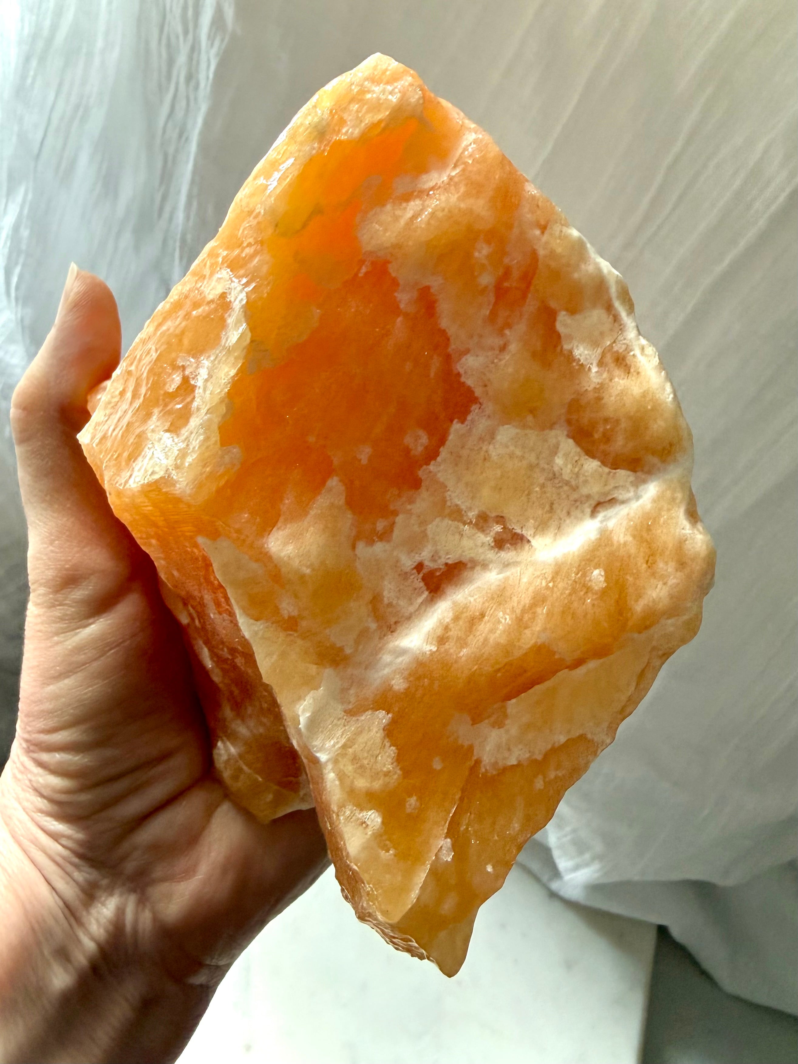 Large self-standing Orange Calcite specimen displaying natural mineral formations and luminous orange translucency