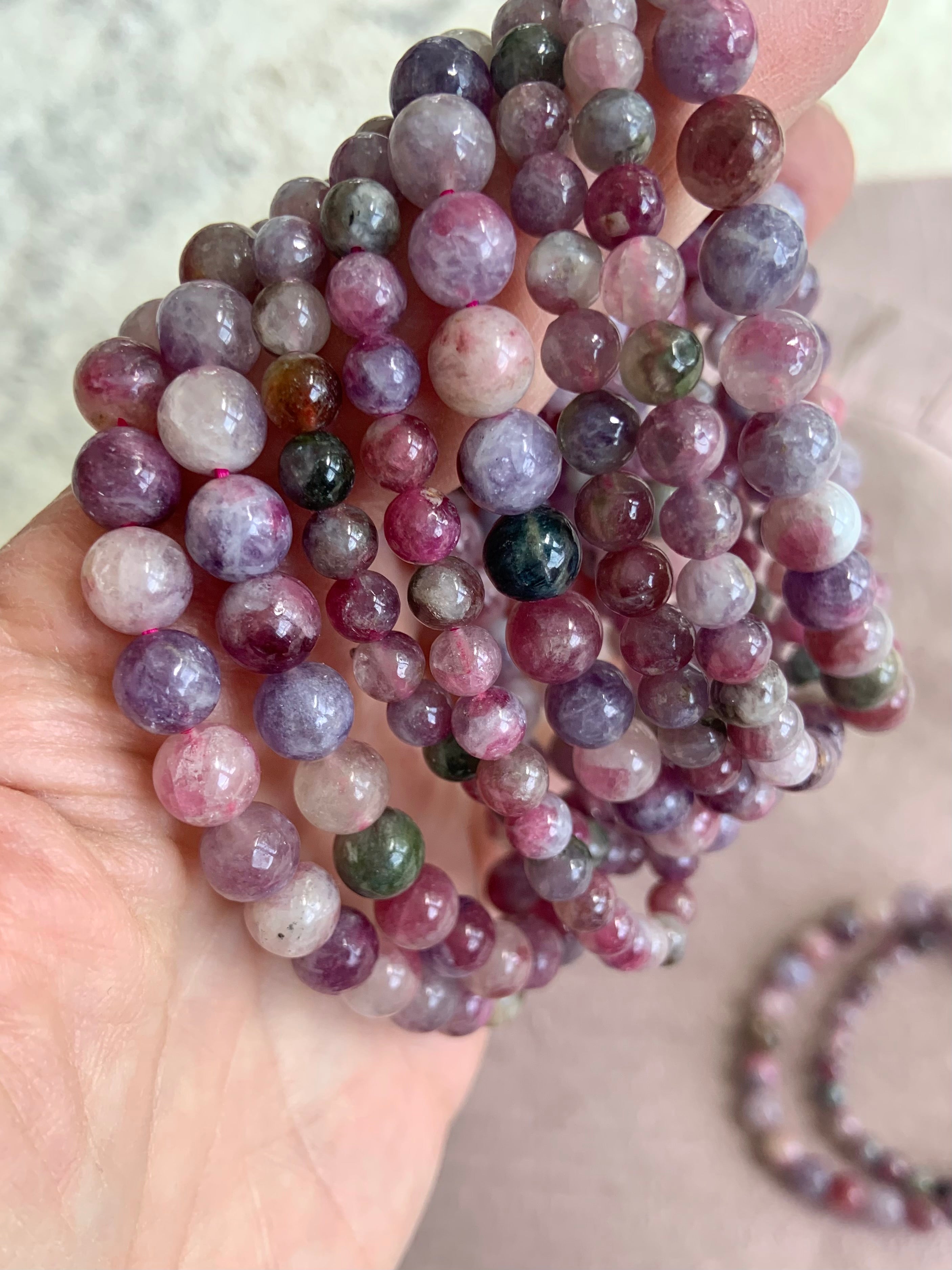 Side view of stacked Green Unicorn Stone bracelets — aka Watermelon Tourmaline in Lepidolite — heart chakra crystal jewelry in mixed bead sizes for anxiety relief + calm