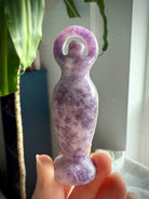A Lepidolite Standing Goddess Statue held up to the light to show the luminous quality of the stone
