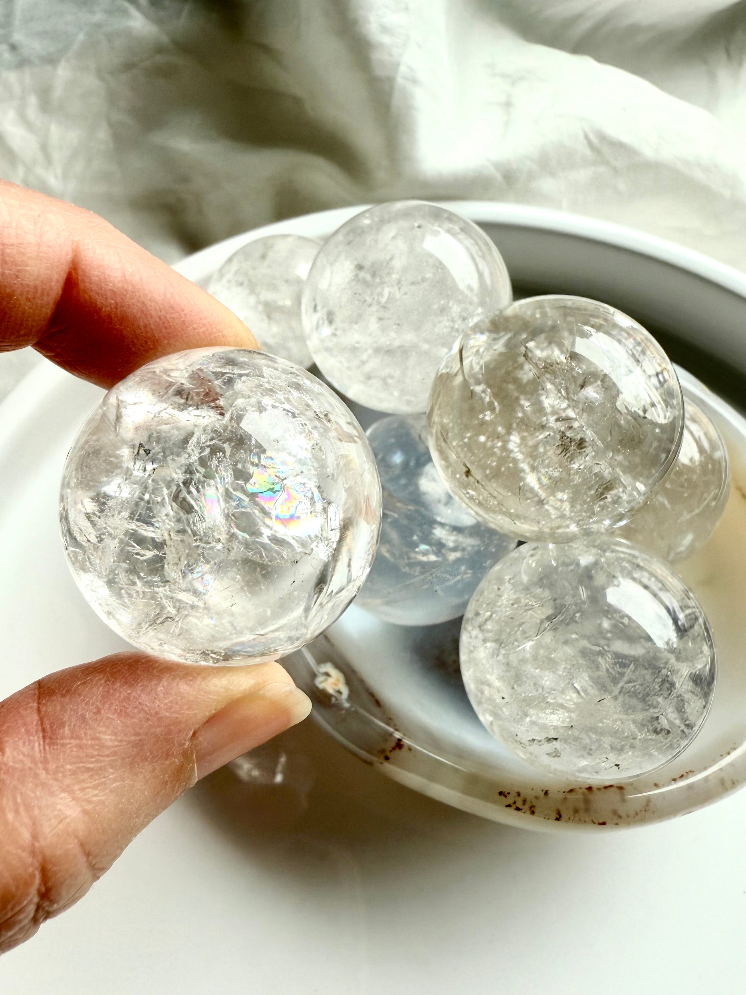 Hand holding a clear Rainbow Quartz sphere with faint rainbow glow – sacred geometry sphere for spiritual clarity and chakra alignment