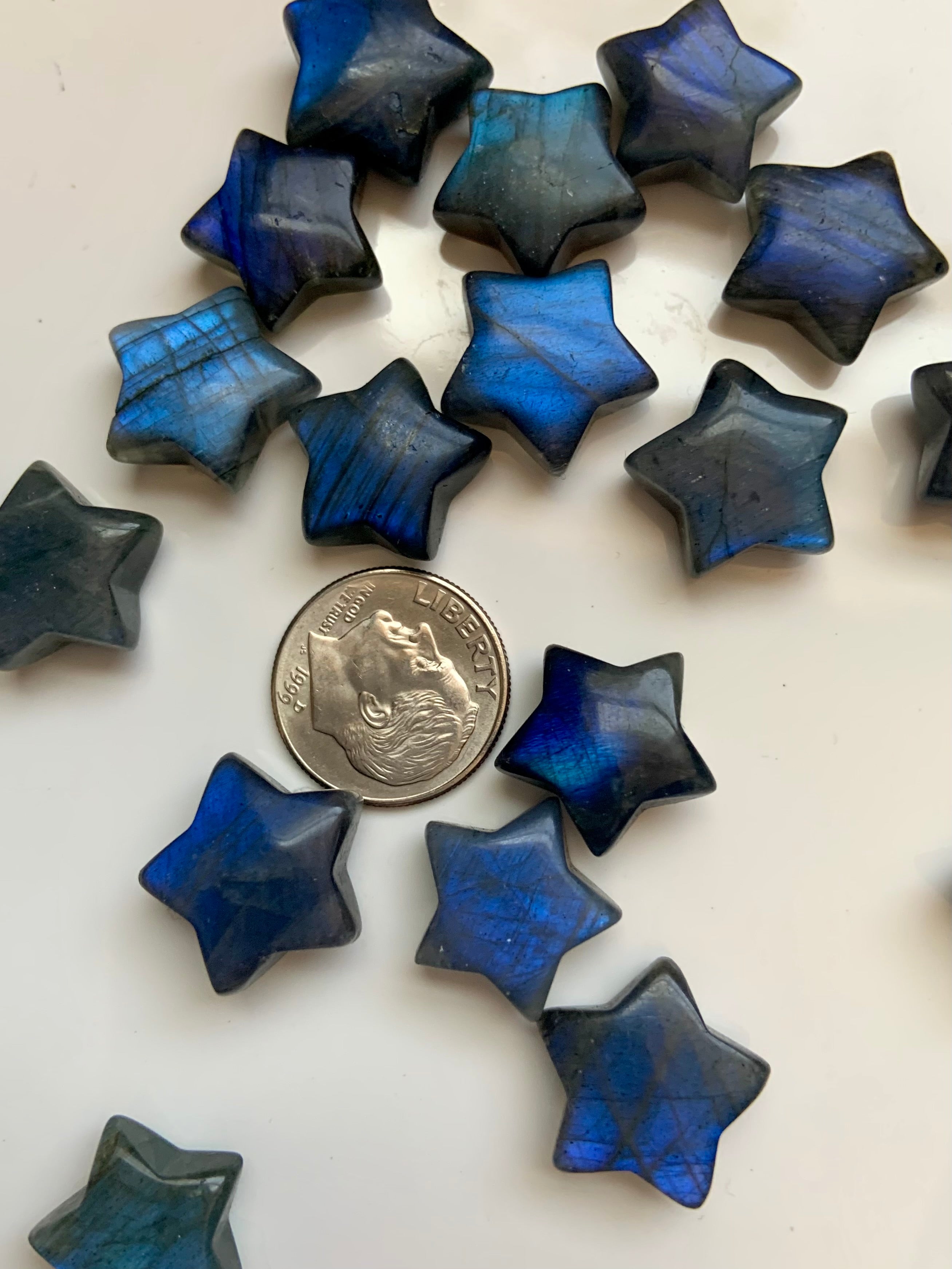 Close-up of deep blue Labradorite crystal stars with a dime for scale — mini star carvings for Third Eye chakra, intuition & energetic shielding.