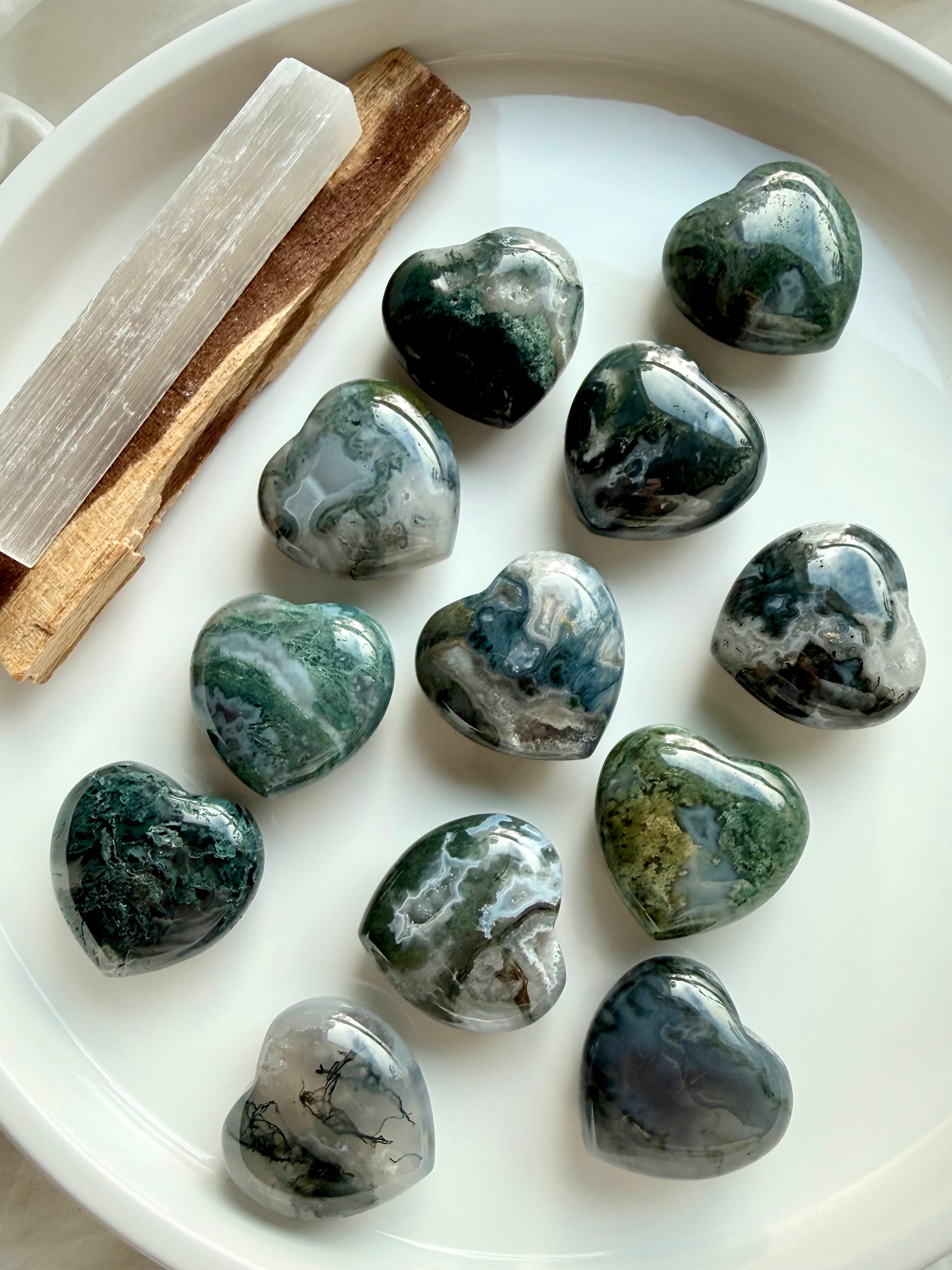 Polished Moss Agate hearts with earthy green inclusions, styled with selenite and palo santo for crystal healing