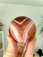 A stunning banded carnelian sphere with an intricate chevron pattern
