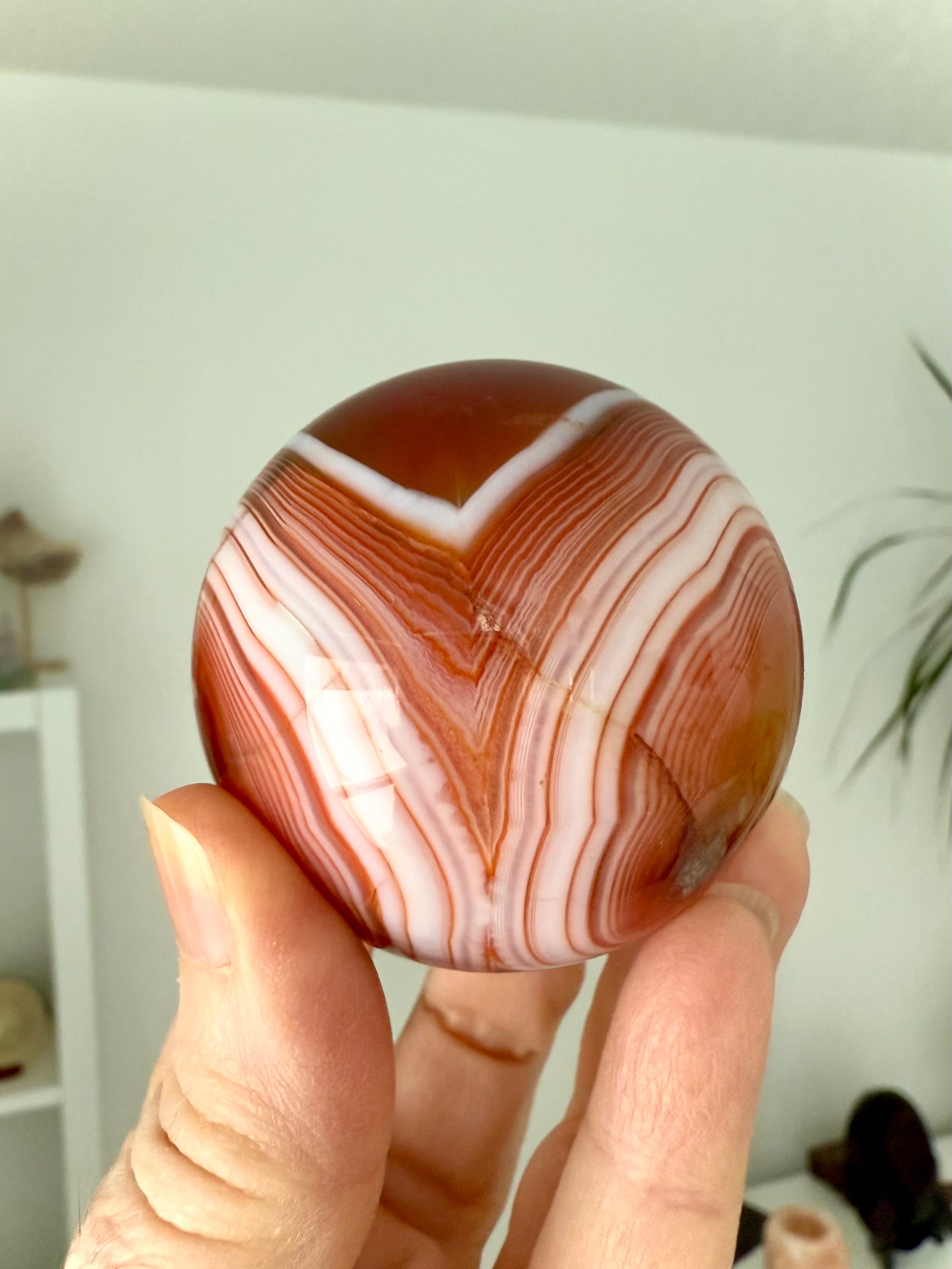 A stunning banded carnelian sphere with an intricate chevron pattern