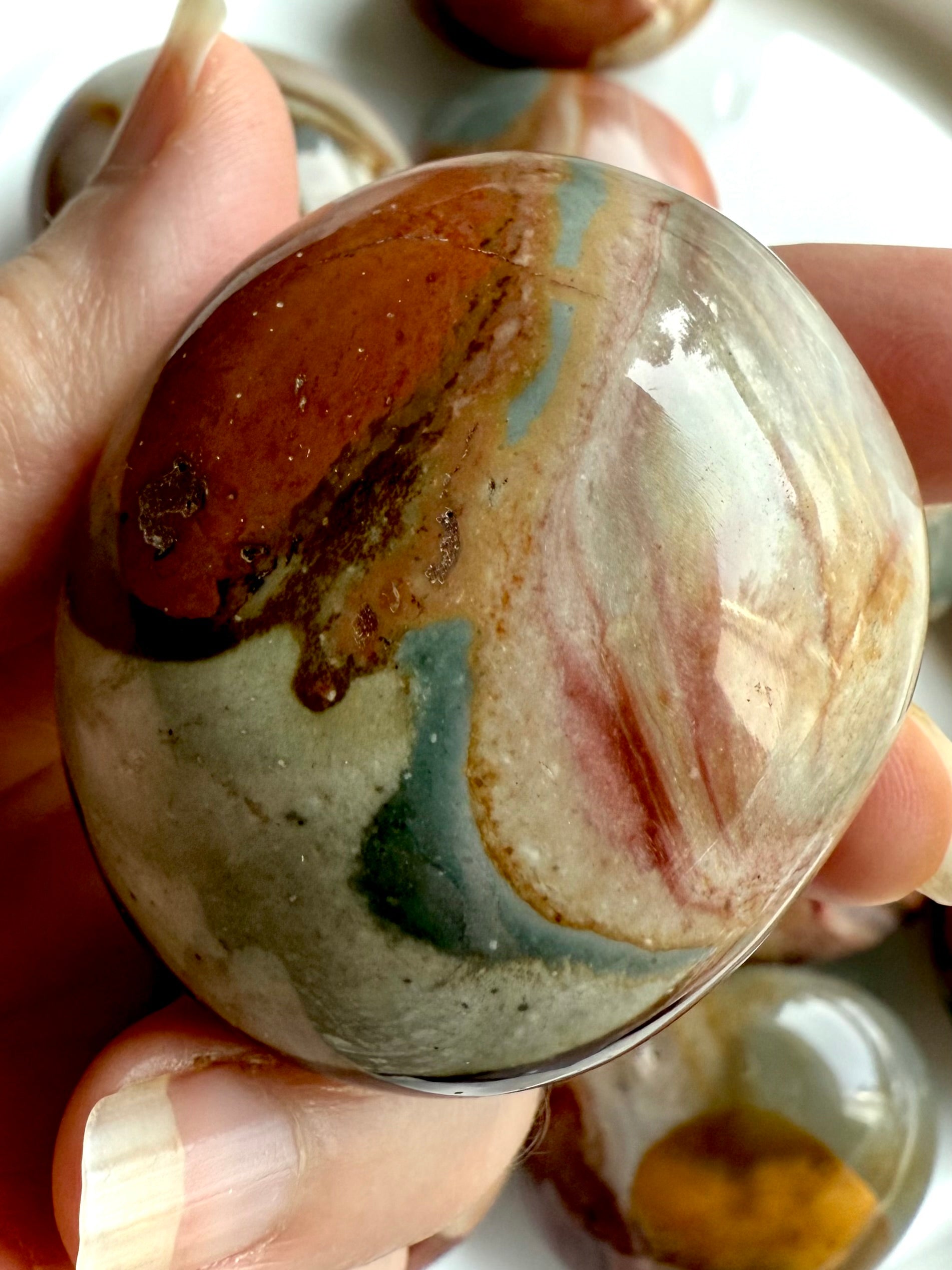 Closeup of a Polychrome Jasper palm stone with earthy tones, unique swirls & grounding crystal energy