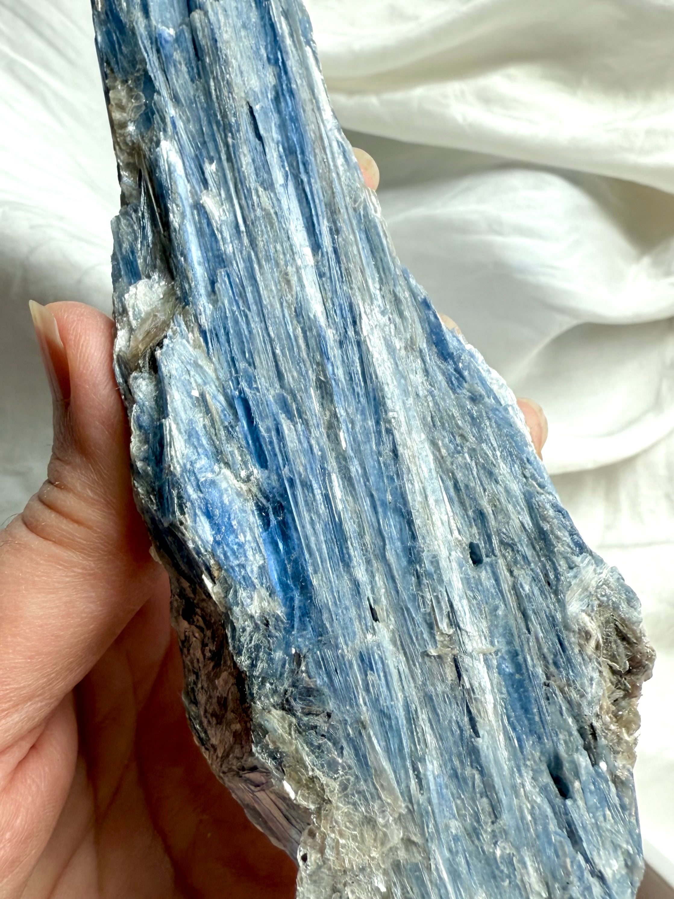 Close up of raw blue kyanite with muscovite mica showing natural flaky crystal texture and silvery shimmer
