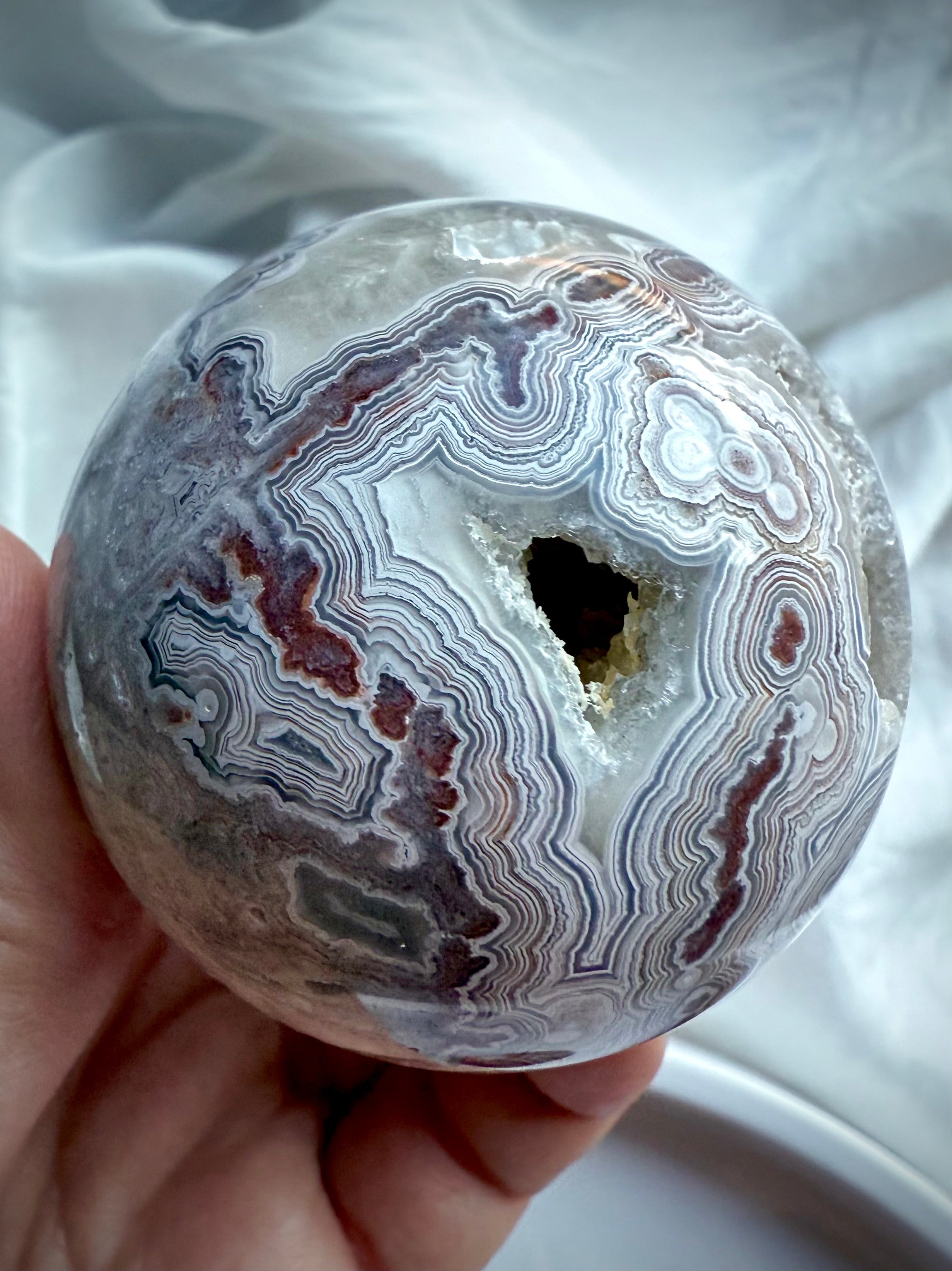 Crazy Lace Agate sphere with sparkling druzy pocket and bold concentric banding in shades of white, grey, and burgundy