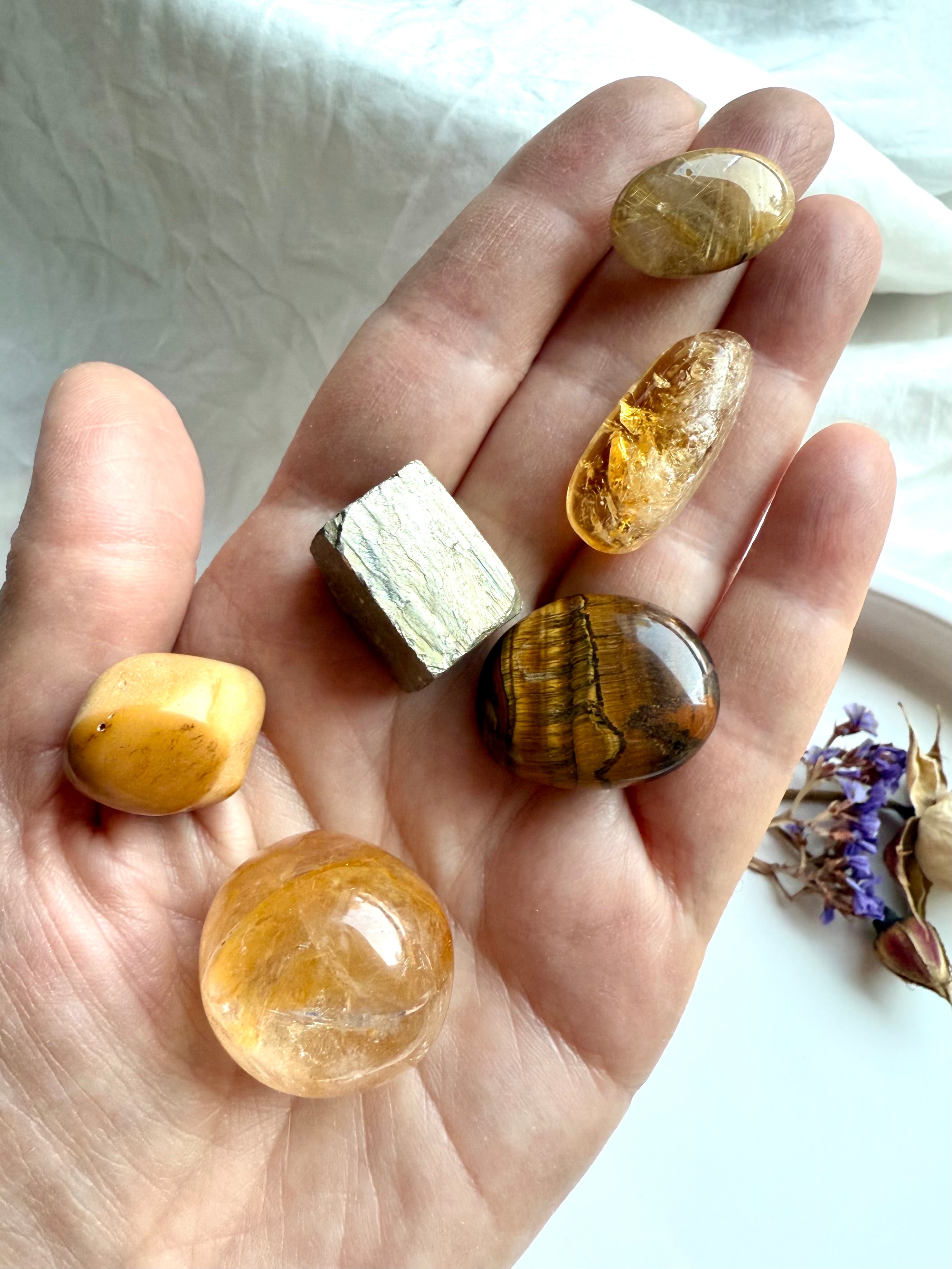 Golden healer, citrine, golden rutile, tiger’s eye, yellow mookaite, and pyrite crystals shown in hand for scale