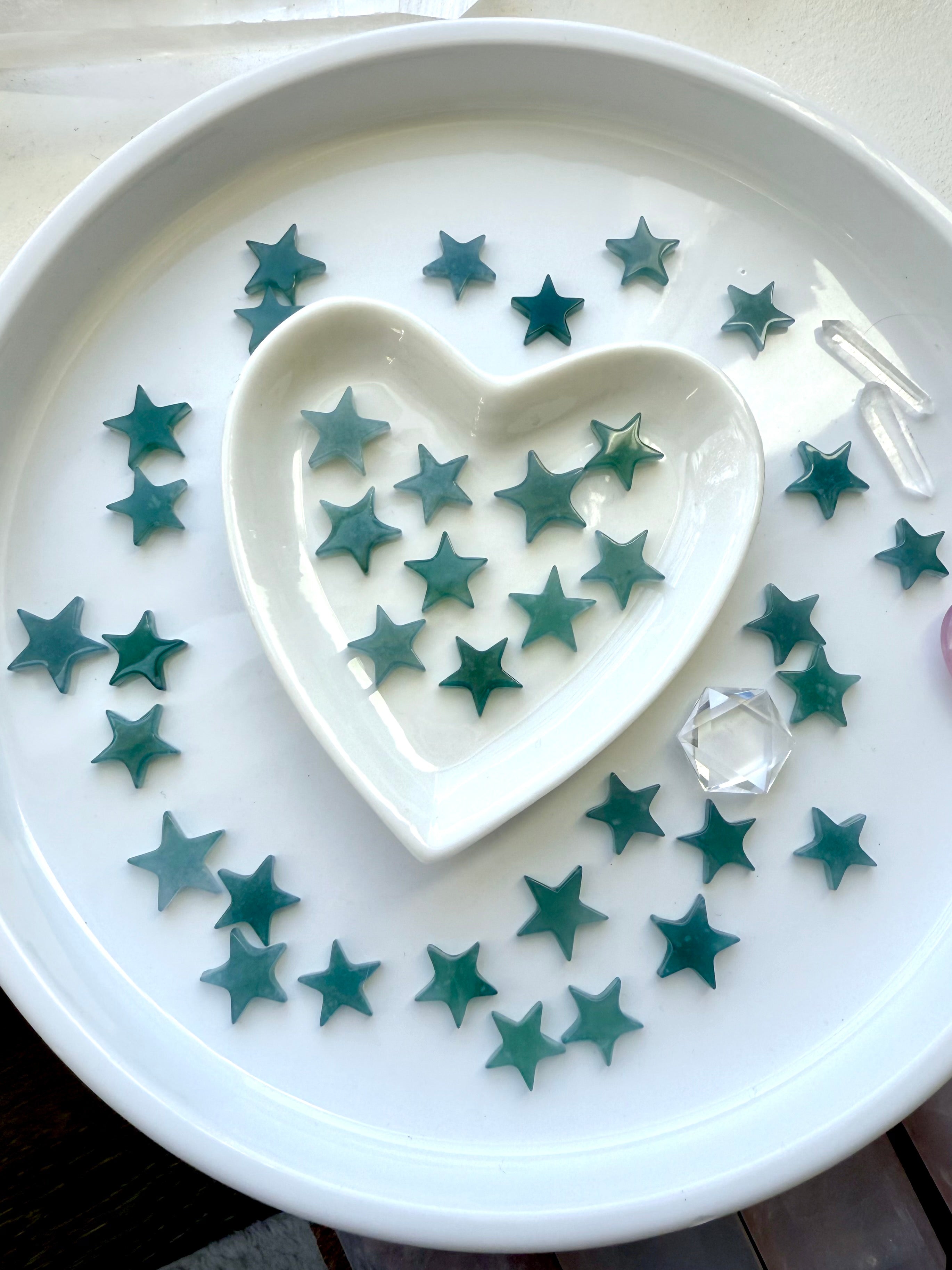 Our Mini Blue Water Jade Stars shown on a white plate photographed in natural ambient light
