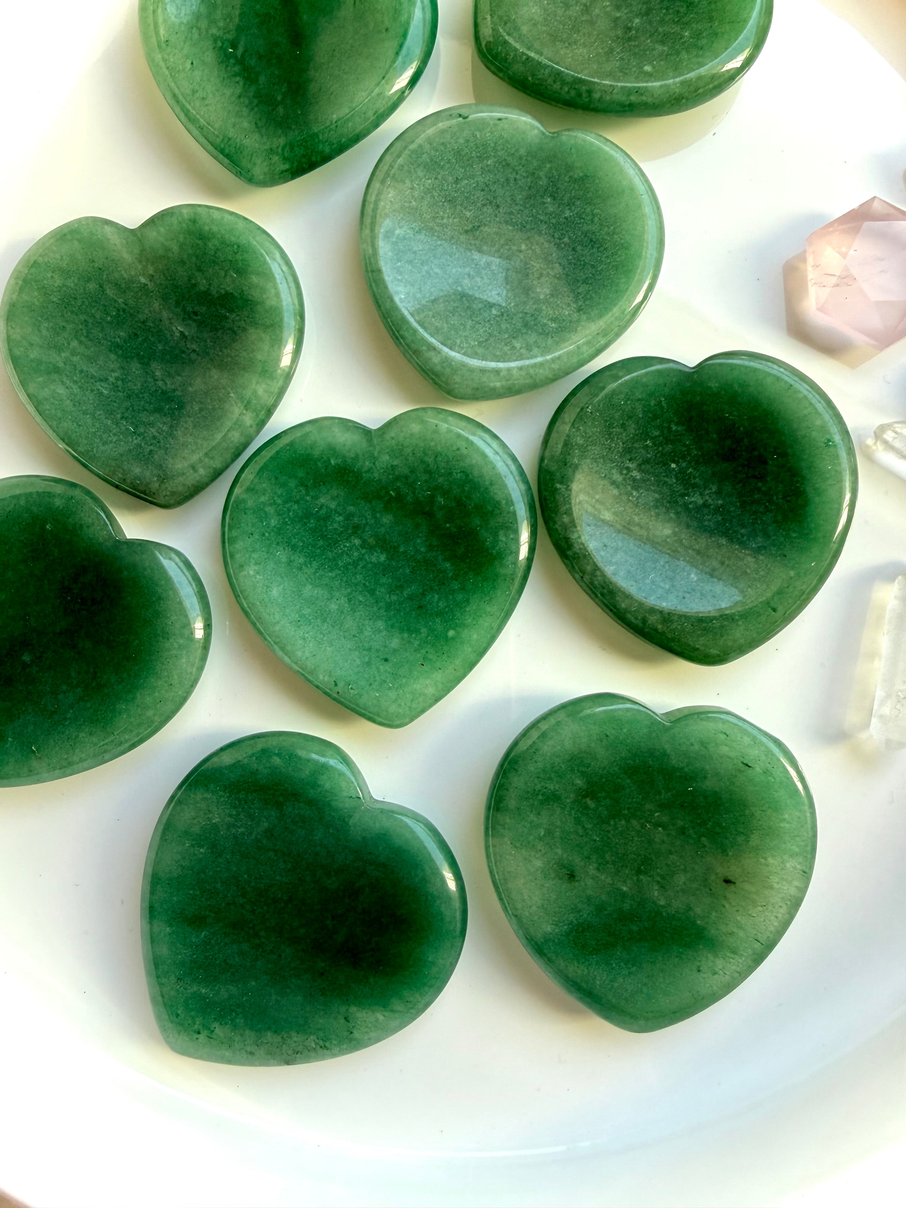 overhead view of green aventurine heart worry stones on white tray, heart chakra crystals for luck, growth and healing