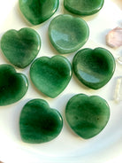 overhead view of green aventurine heart worry stones on white tray, heart chakra crystals for luck, growth and healing