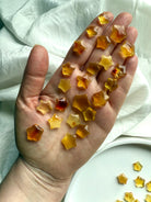 Hand holding Mini Amber Star carvings – golden crystal stars for Solar Plexus chakra healing and warmth