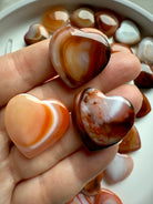 Mini Carnelian heart held in hand, small polished sacral chakra crystal for creativity, passion, and joyful energy
