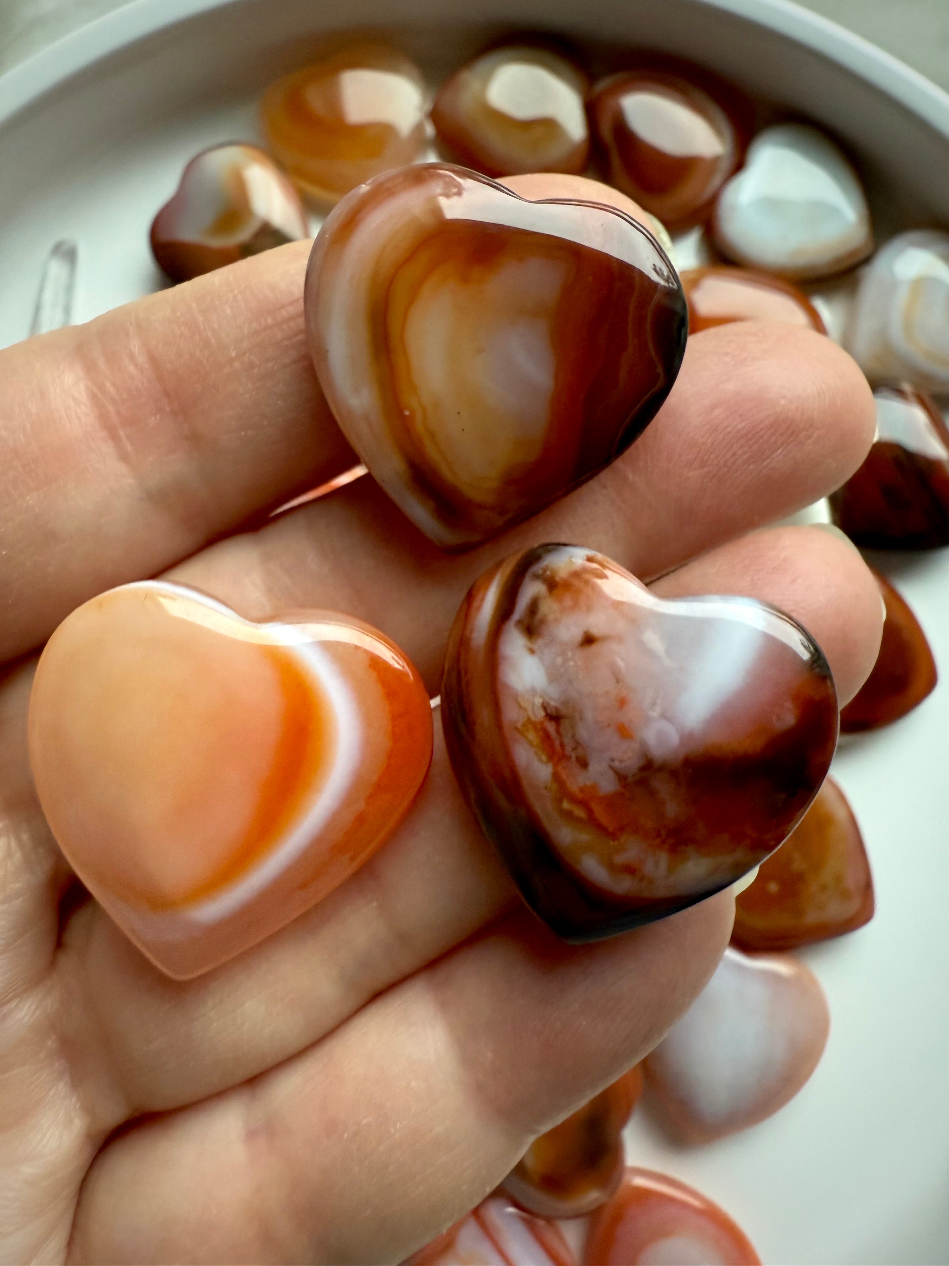 Mini Carnelian heart held in hand, small polished sacral chakra crystal for creativity, passion, and joyful energy