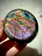 Polished Labradorite palm stone showing luminous purple and pink flash with brilliant gold and electric blue accents