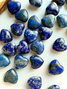 Mini Lapis Lazuli heart crystals scattered on a white surface, polished gemstone hearts highlighting natural color and texture differences