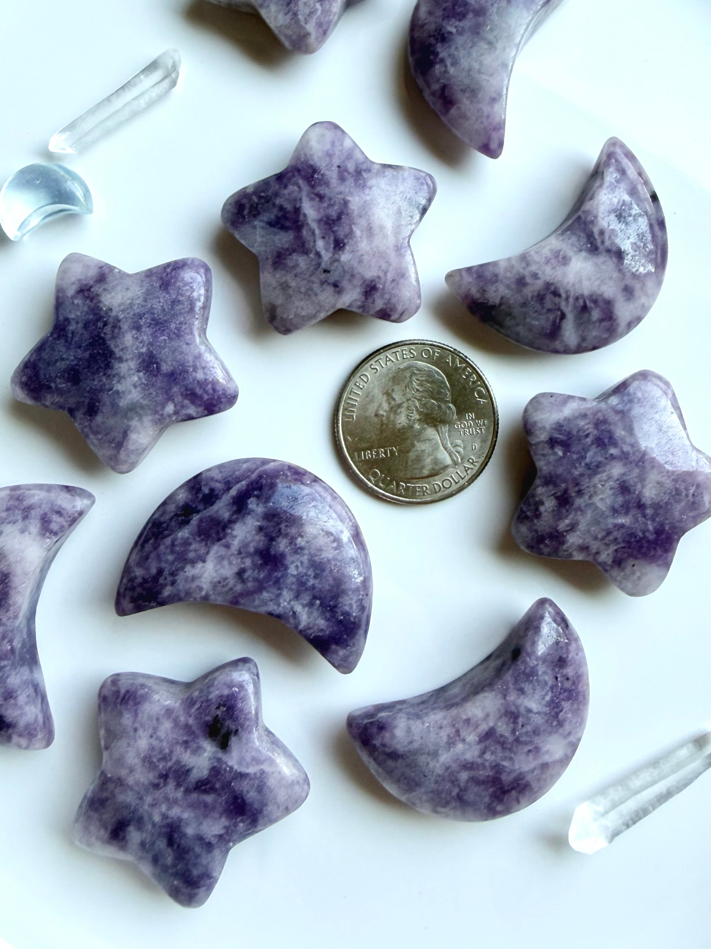 Lepidolite moon and star crystals arranged with US quarter for scale showing the size of the polished celestial carvings