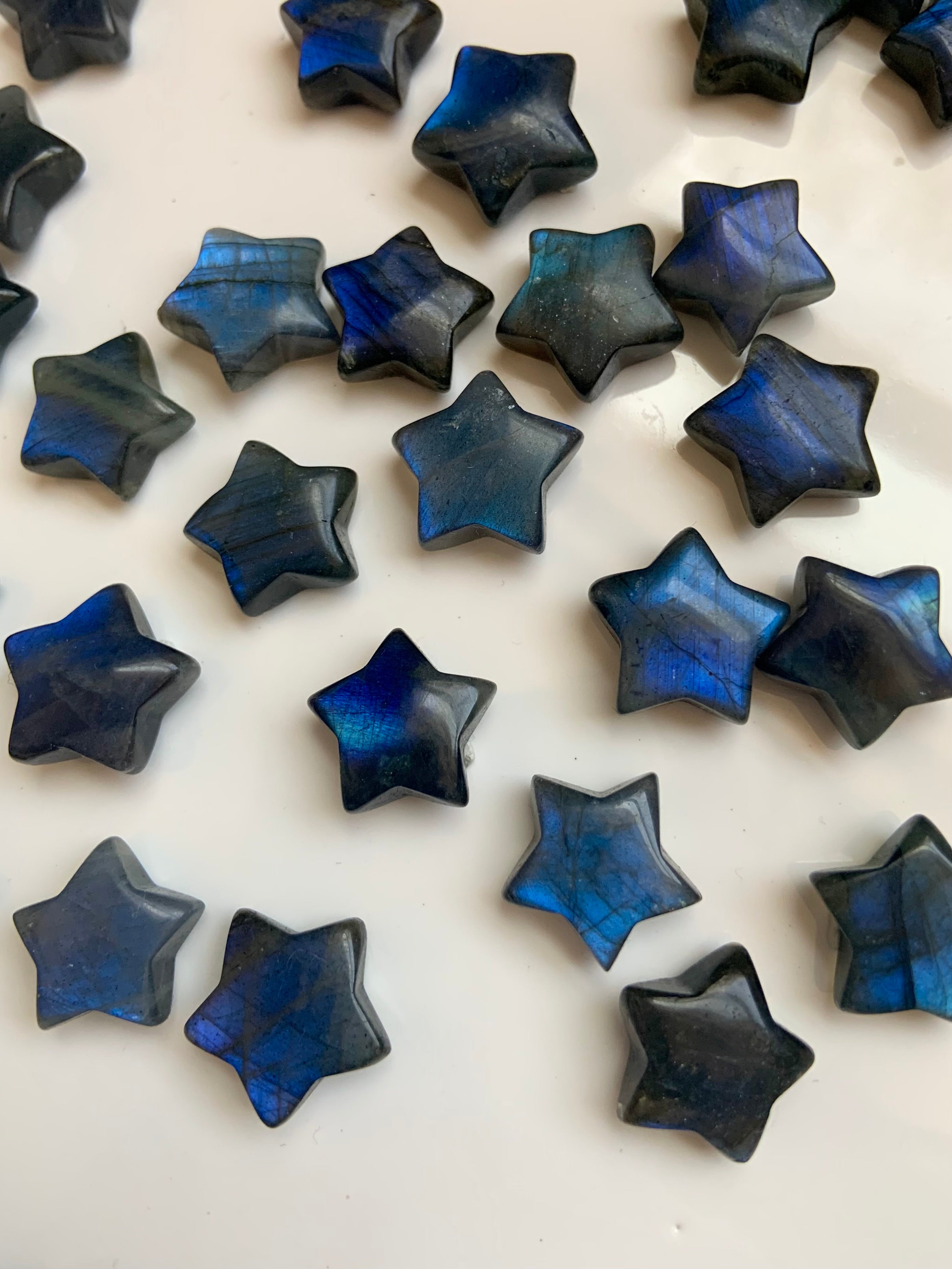 Close-up of deep blue flash Labradorite crystal stars on white background — shimmering mini star crystals for Third Eye chakra, aura protection & intuitive insight.