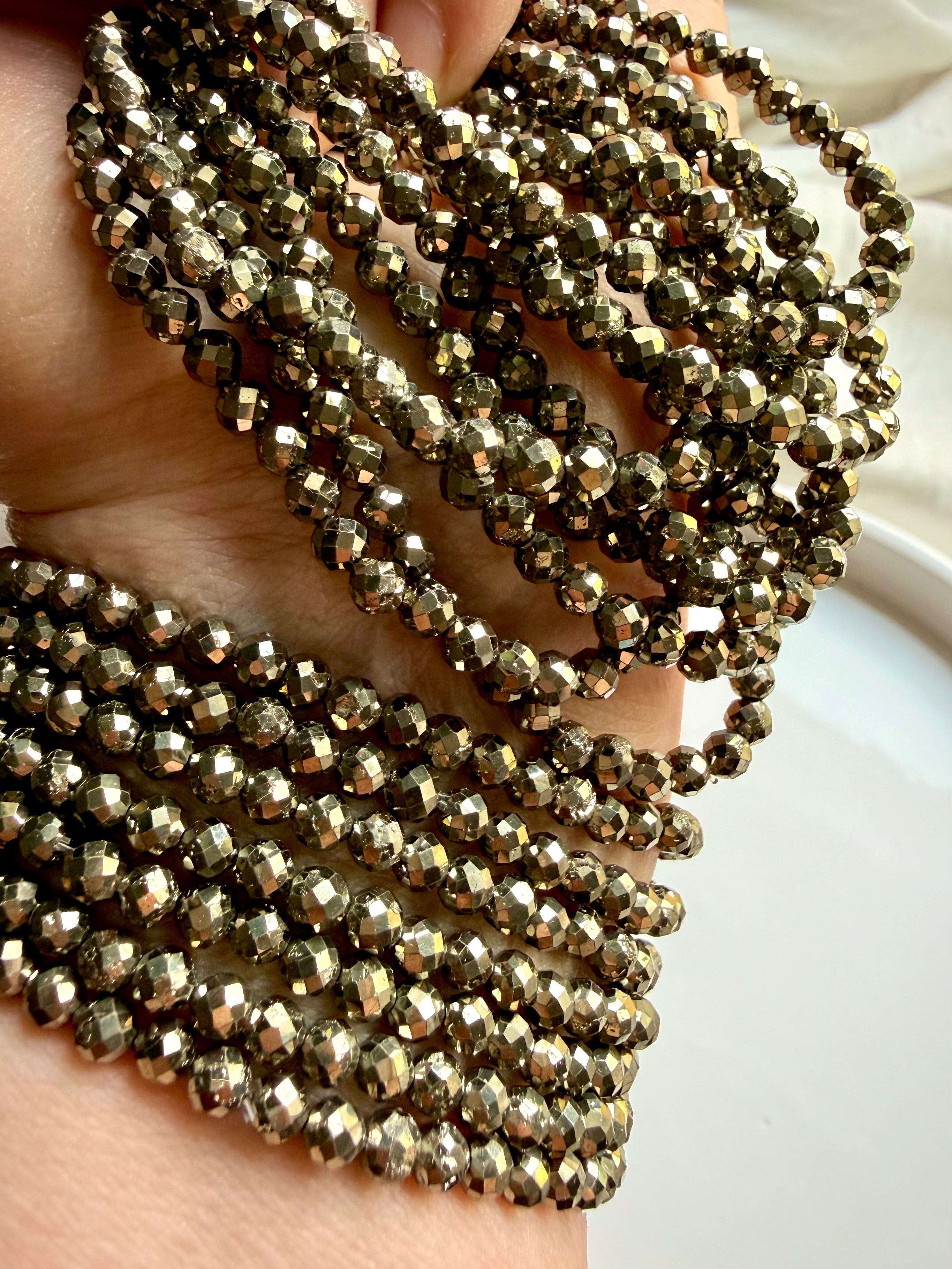 multiple pyrite bead bracelets cascading in hand showing golden sheen and abundance crystal energy