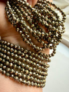 multiple pyrite bead bracelets cascading in hand showing golden sheen and abundance crystal energy