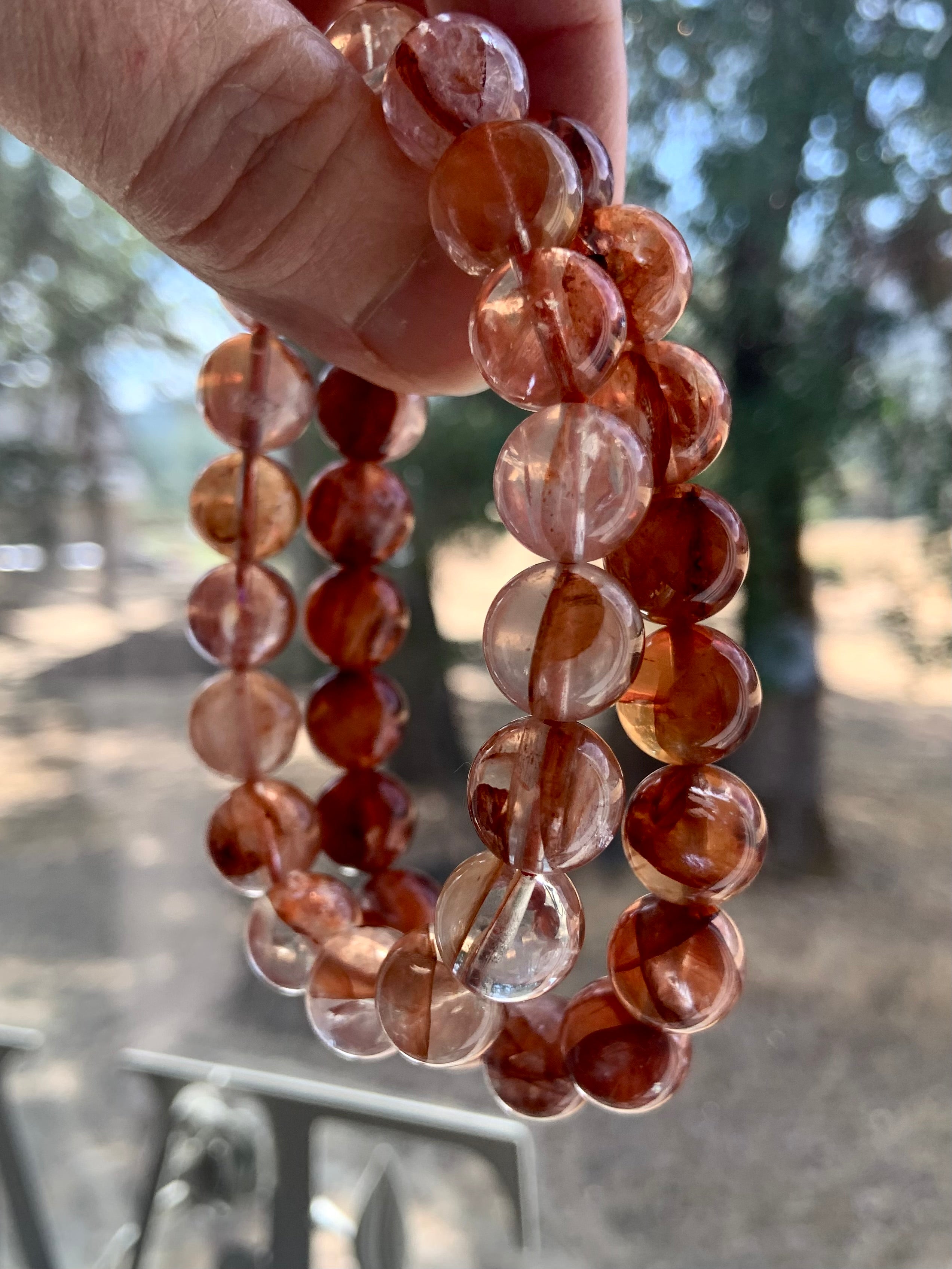 Two Fire Quartz bracelets held up to show color variation between light and dark red quartz options