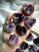 dream amethyst heart worry stones shown on hand with chevron banding for calming energy