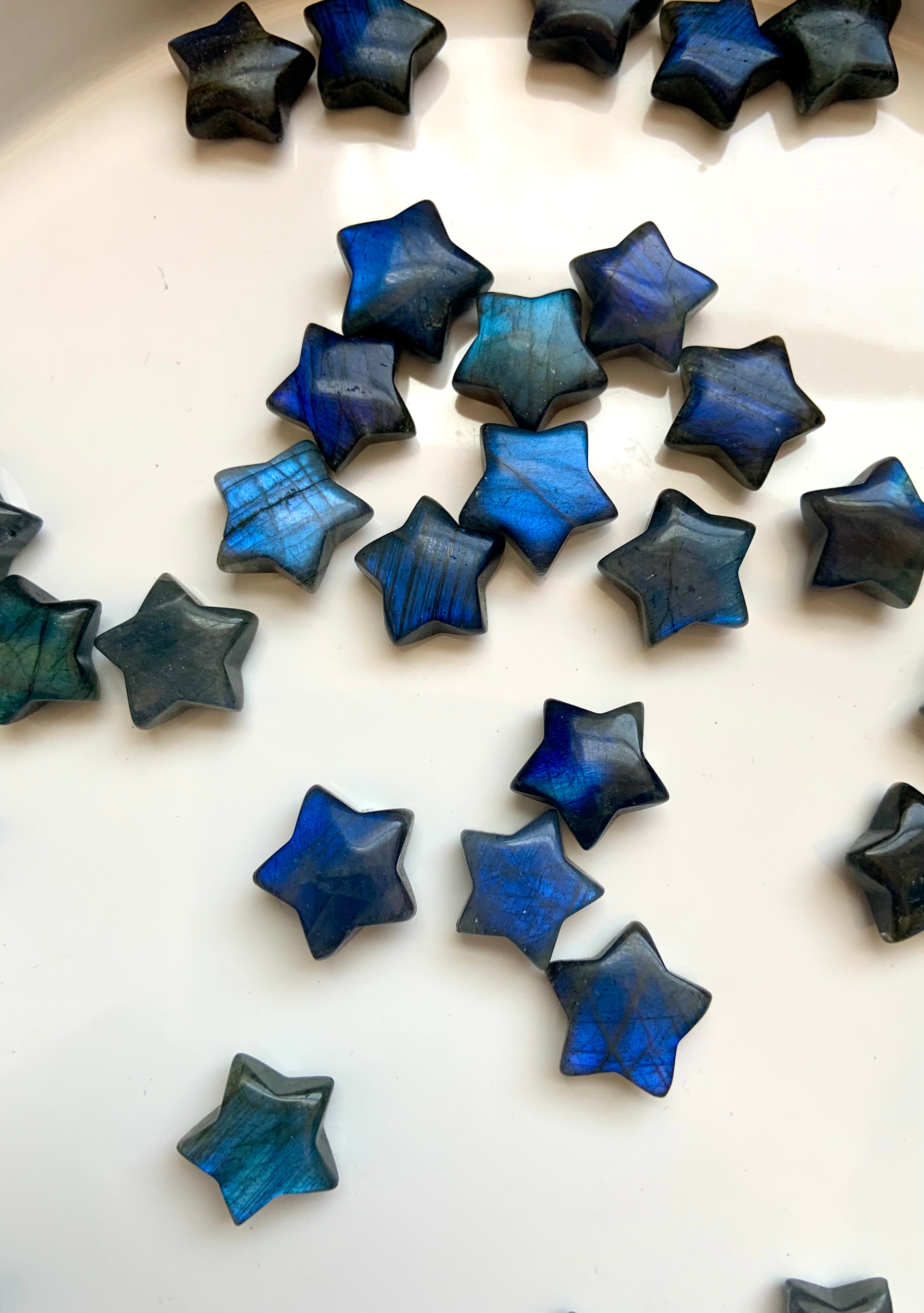 Deep blue Labradorite mini crystal stars arranged on white — radiant star carvings for psychic insight, mental clarity &amp; energetic protection.