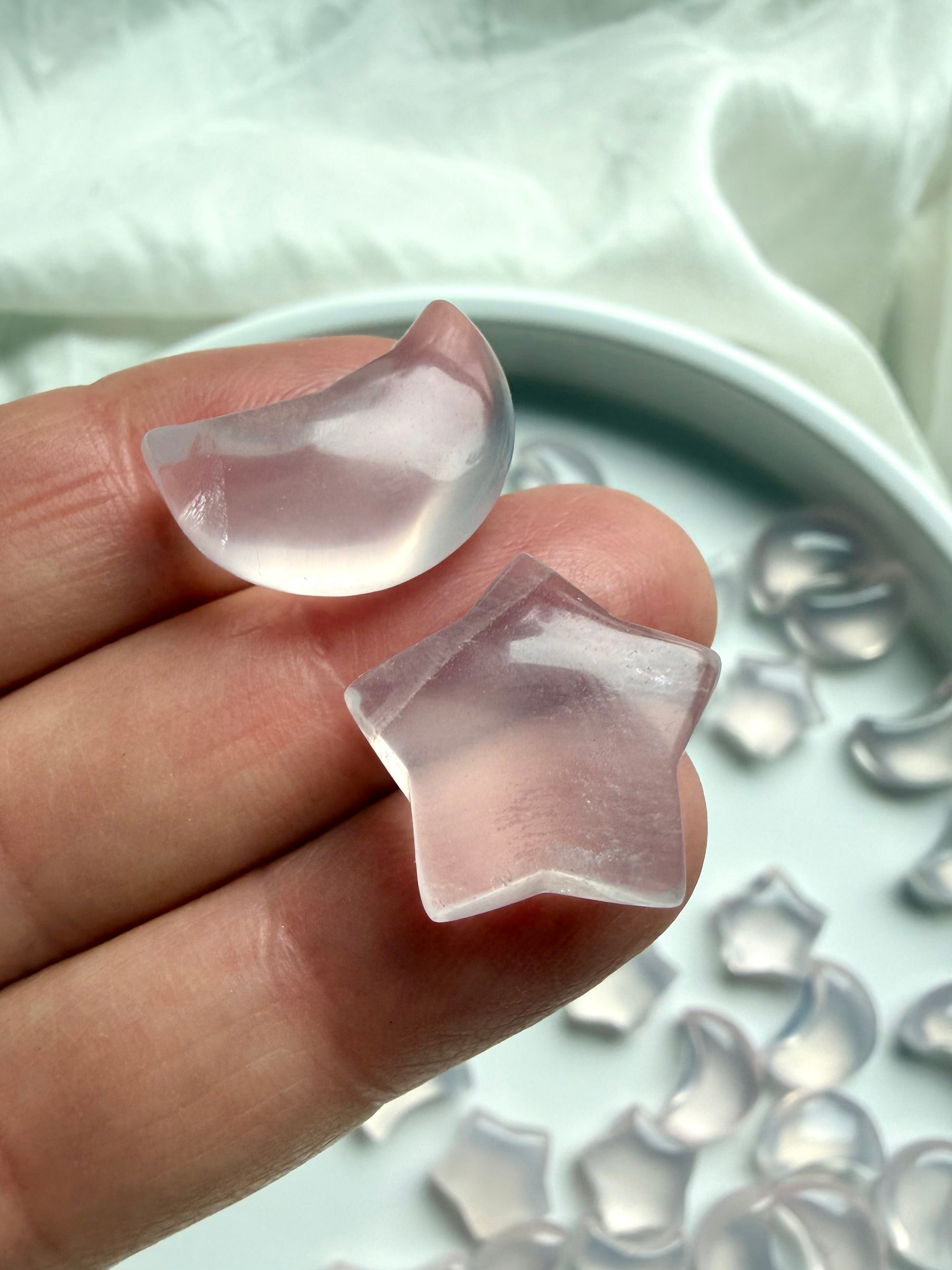 Mini Rose Quartz crescent moon held in hand showing translucent pale pink color and polished finish