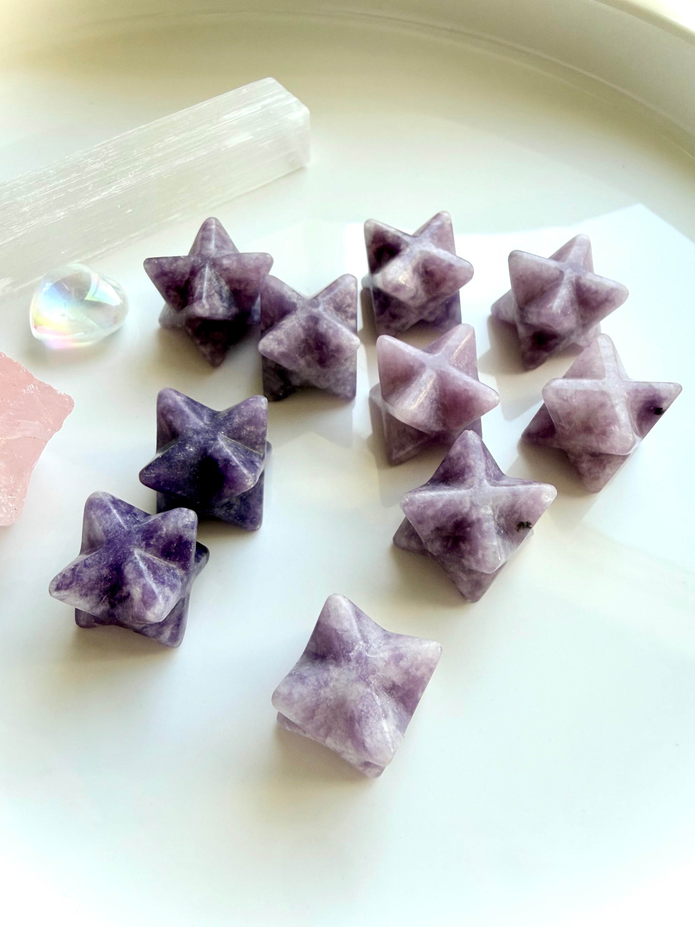 small lepidolite star carvings scattered on soft neutral background, soothing crystals for calm energy and emotional support