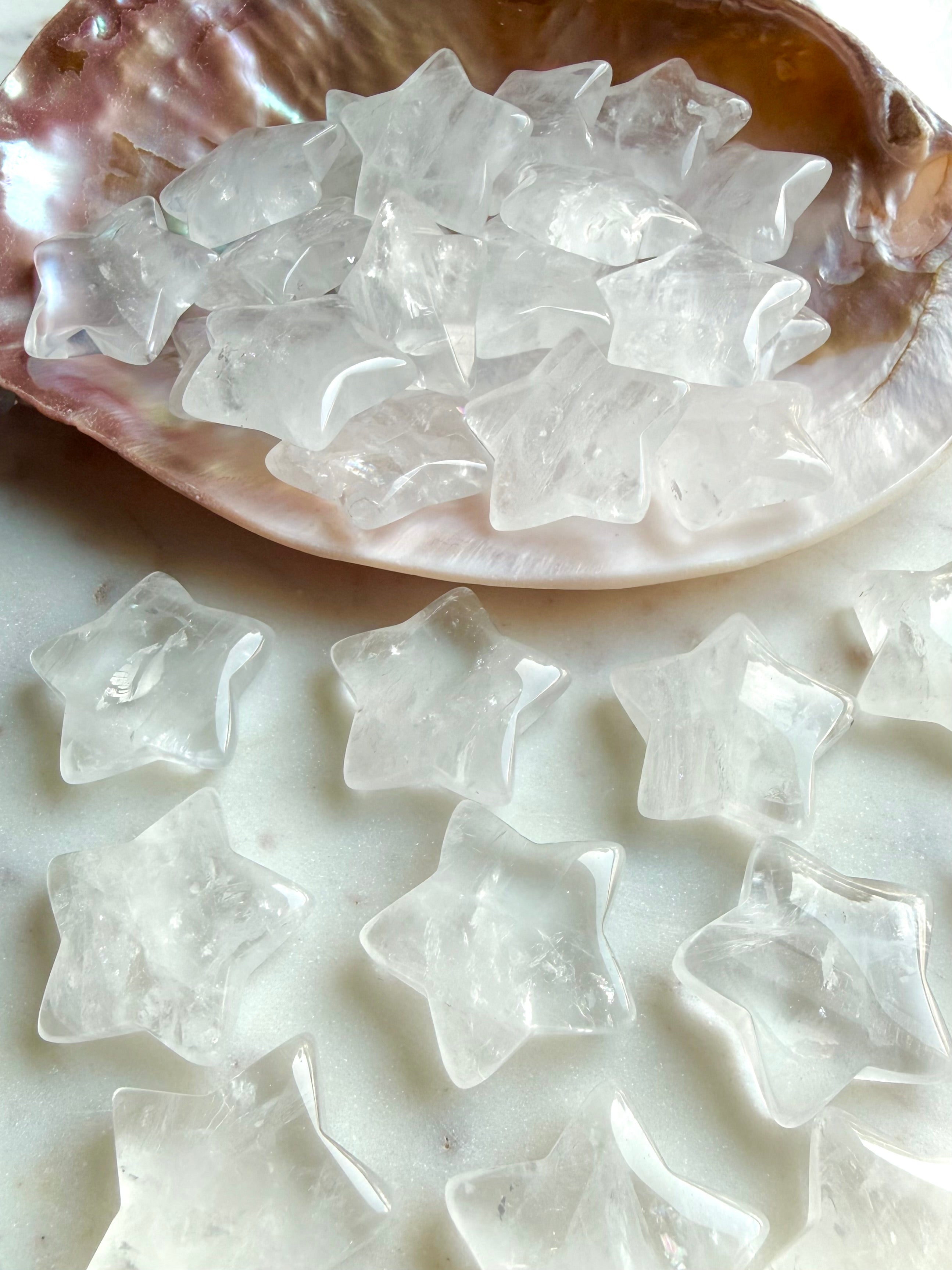 Clear Quartz stars spilling from a shell onto granite surface, celestial crystals for chakra healing and altar décor