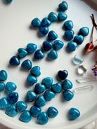 Multiple mini Blue Apatite hearts displayed together, showing variation in color saturation, patterning, and organic crystal character