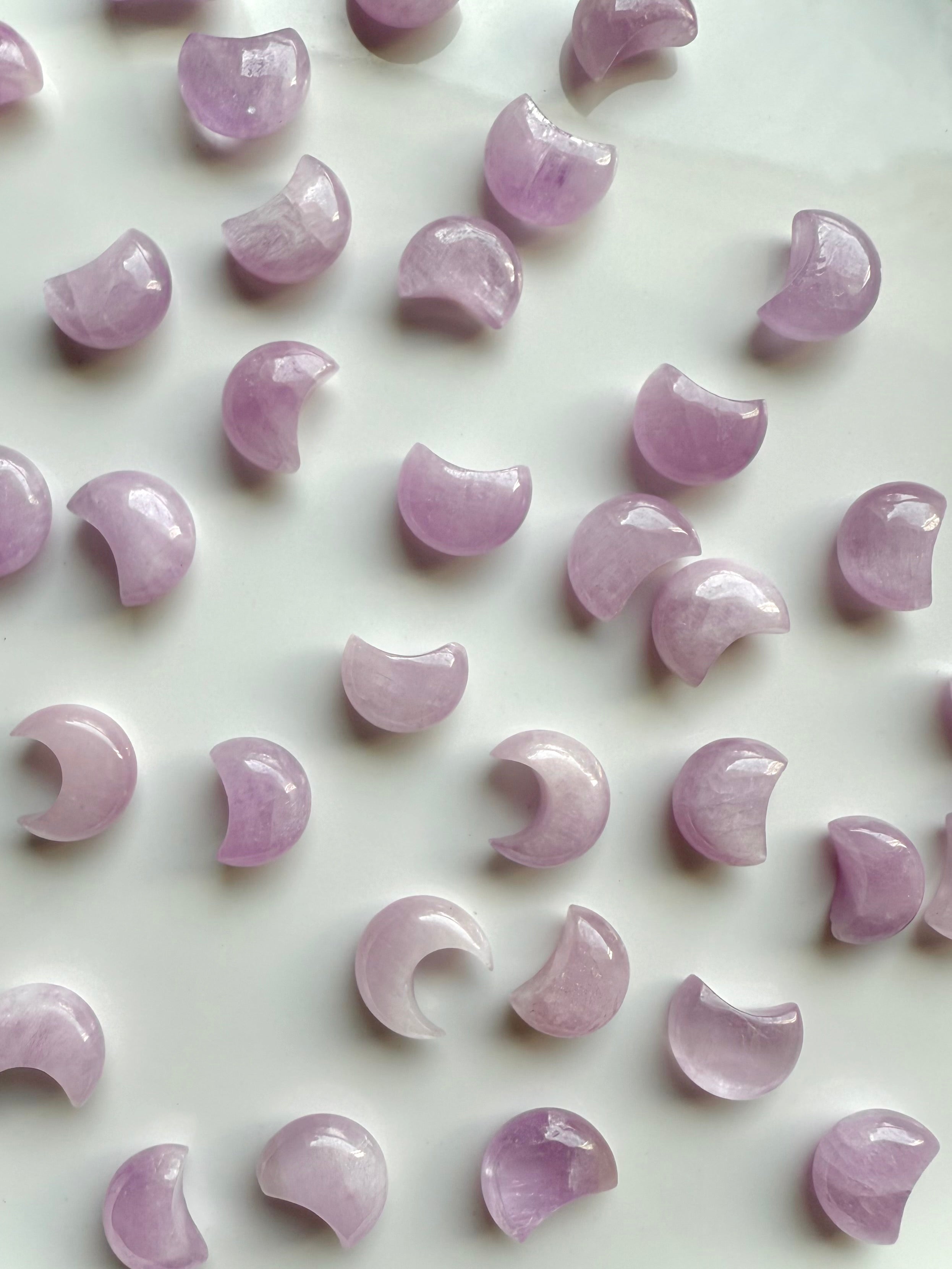 Mini Pink Kunzite crescent moons on a white plate — soft pink crystal carvings for heart-centered healing & emotional harmony.