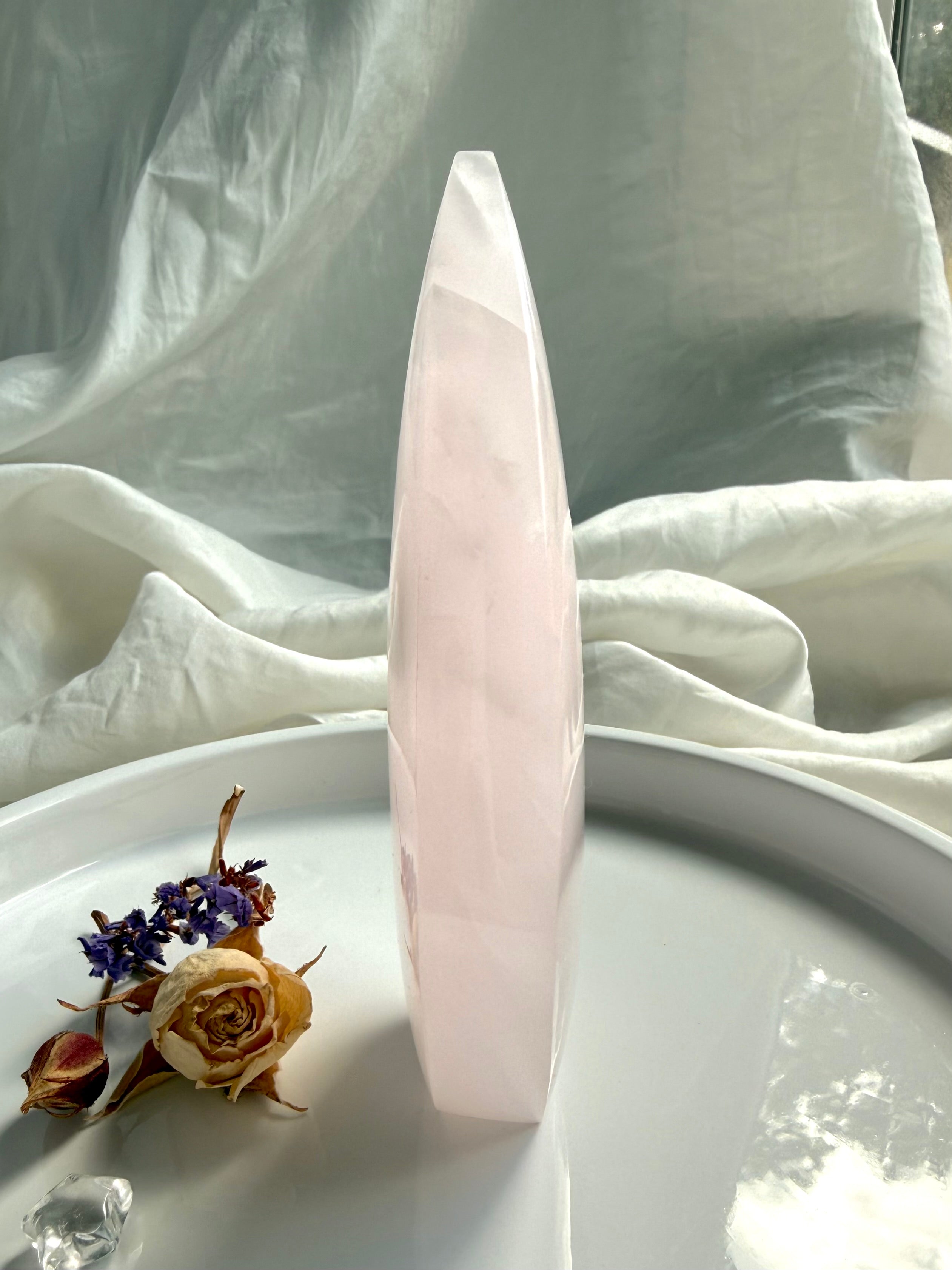 Side view of Mangano Calcite flame carving showing slender profile, soft translucency and polished crystal surface 