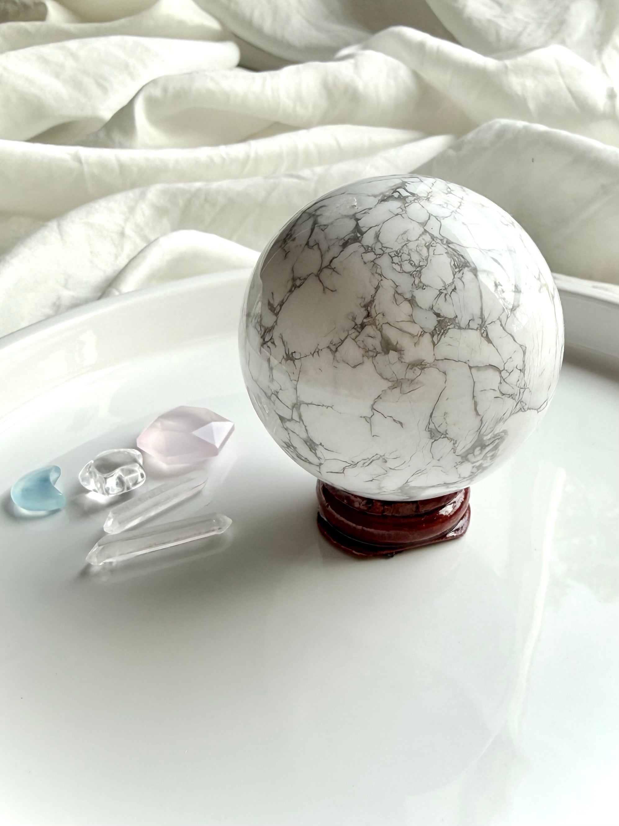 Howlite crystal sphere on wooden stand with rose quartz and clear quartz accents, calming stone for emotional healing and sleep