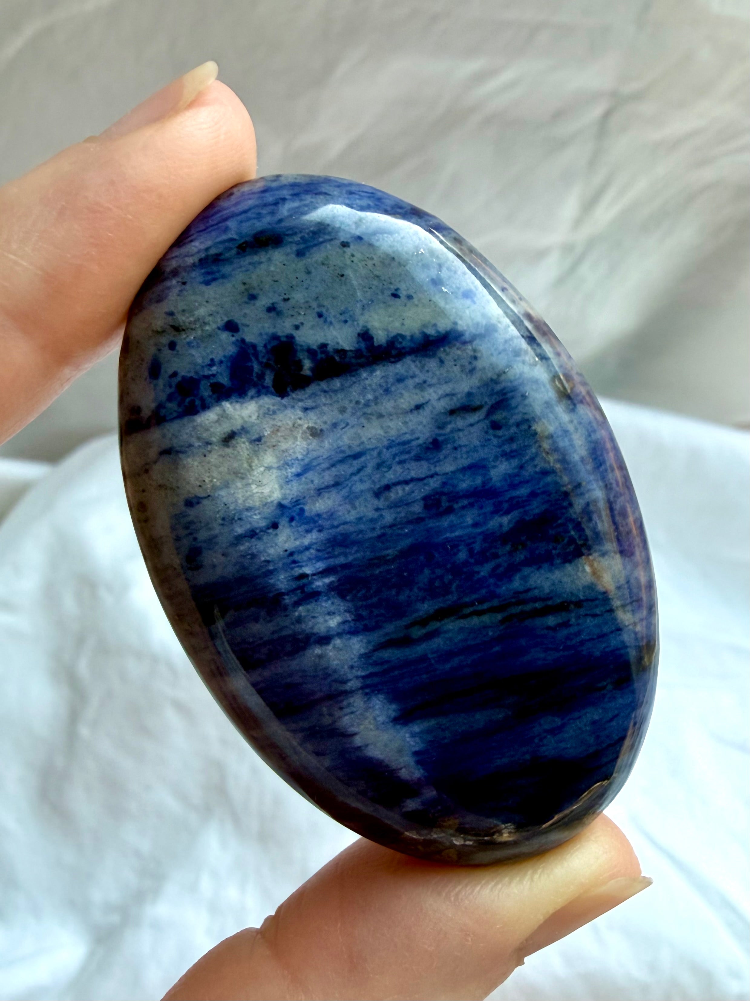 Polished Sodalite palm stone with deep blue color and natural white and gray mineral veining