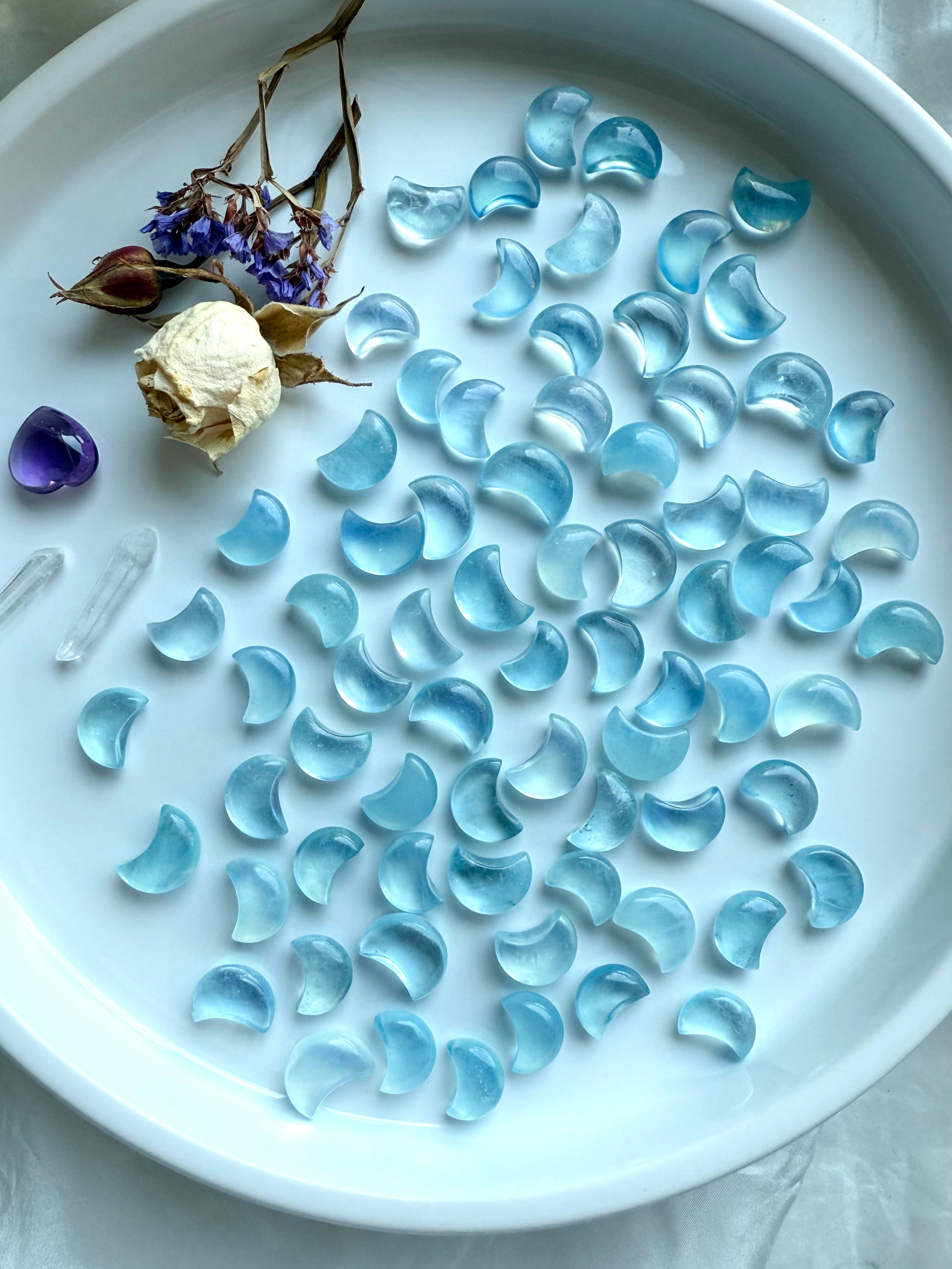 Celestial display of Aquamarine moon carvings with dried botanicals and amethyst heart — gemstone moons for March birthstone gifts and crystal healing
