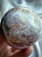 High-quality crazy lace agate sphere with crystalline druzy pocket and fine white, beige, and pink agate bands