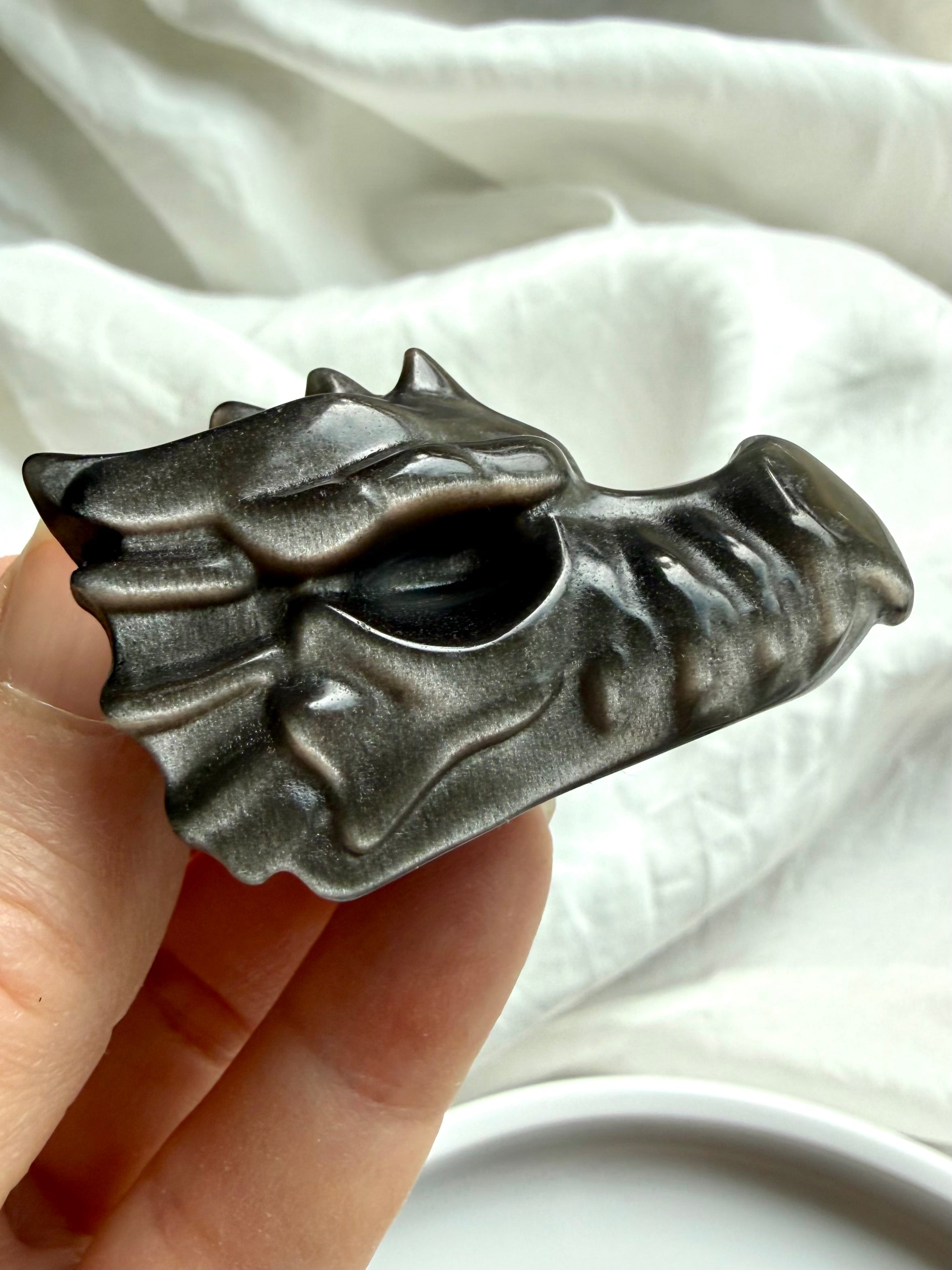 silver sheen obsidian dragon carving with glossy black finish and subtle metallic flash, crystal for protection shadow work and grounding energy