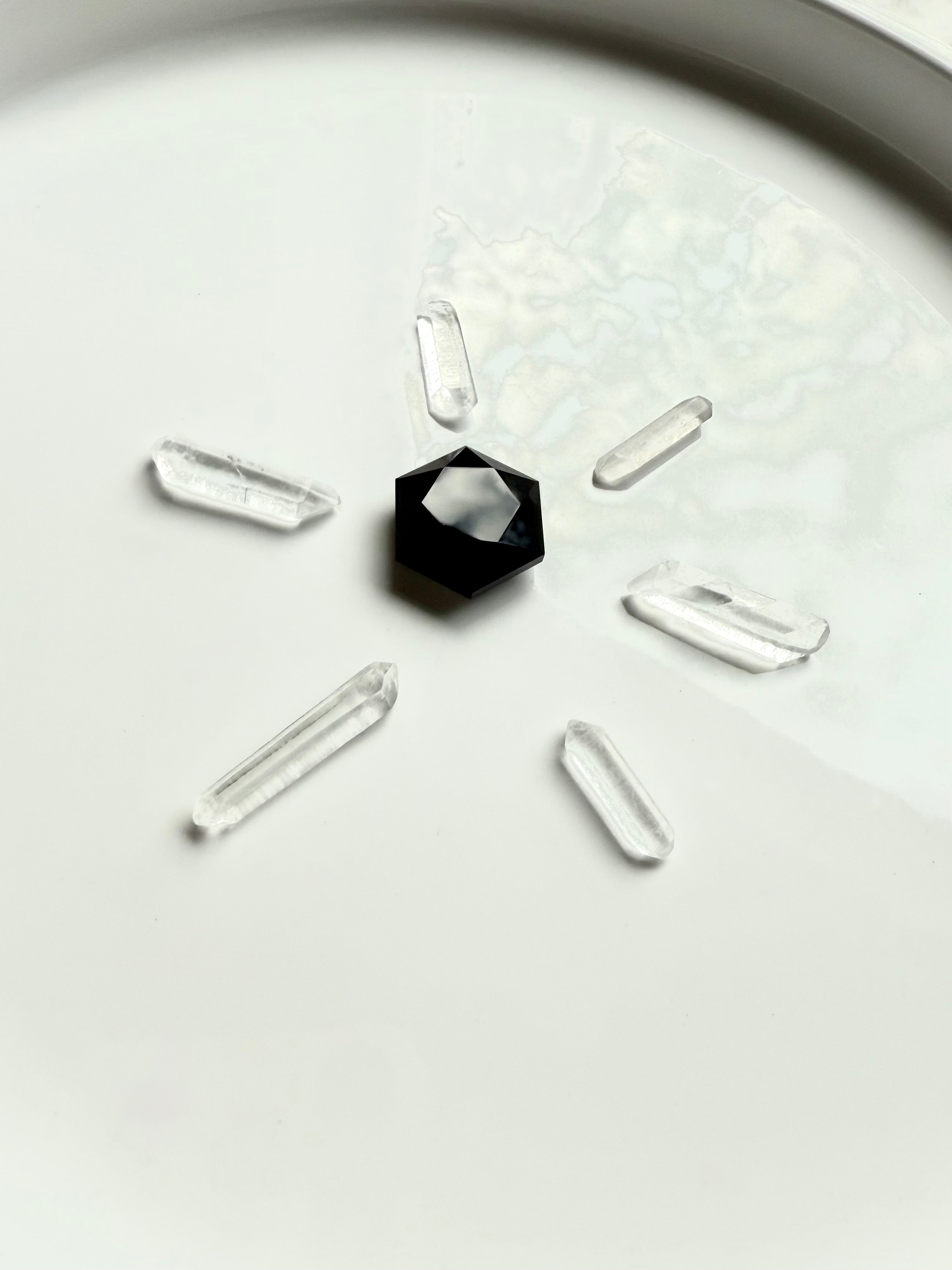 Black Obsidian hexagon crystal in sacred geometry grid layout, placed at center with six clear quartz points radiating outward for energy amplification