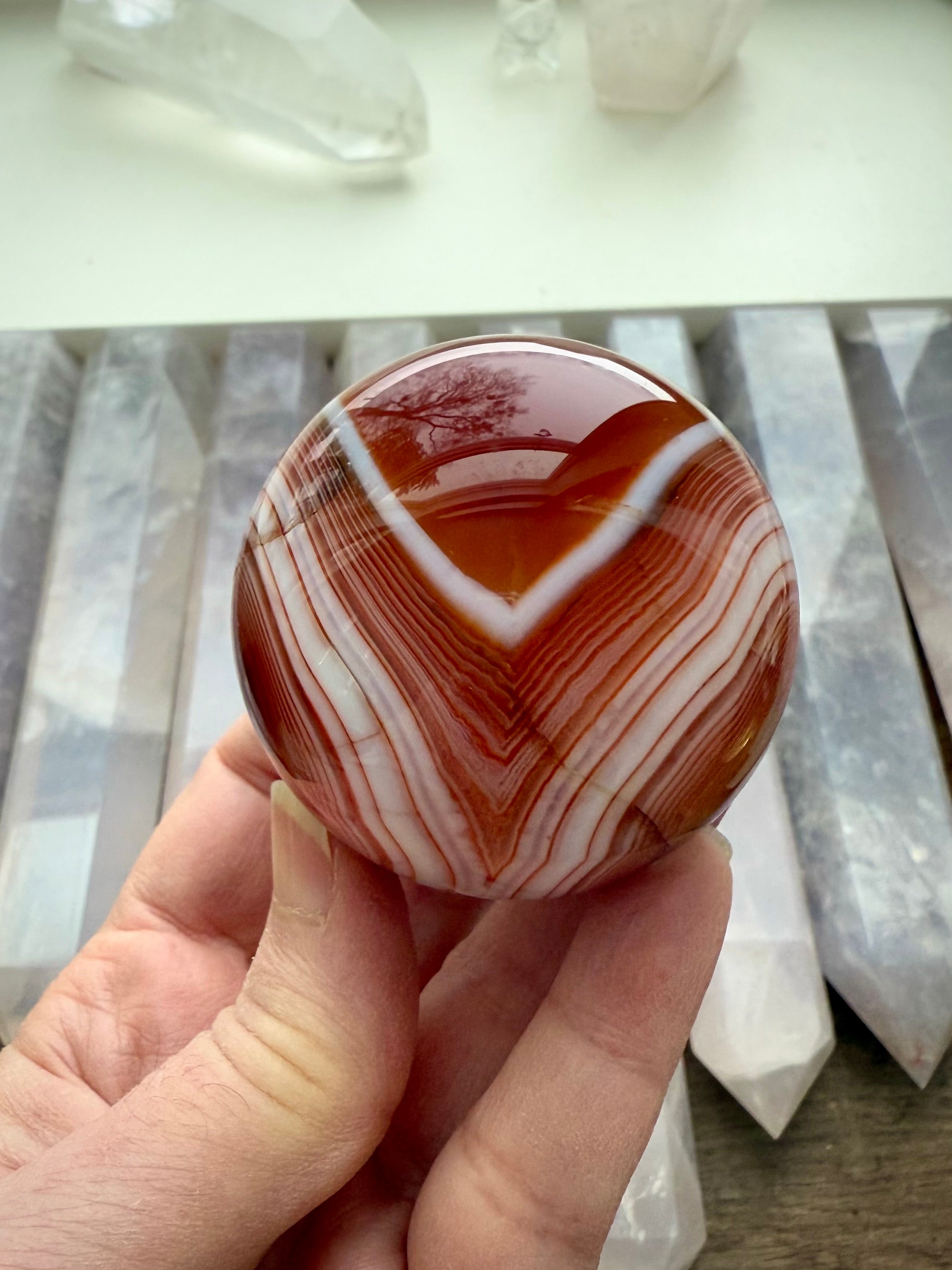 A stunning banded carnelian sphere with an intricate chevron pattern