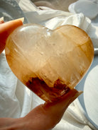 Golden Healer quartz heart held in palm with warm golden hues and natural iron inclusions for confidence and Solar Plexus healing