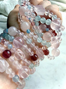 mixed gemstone bracelet stack on wrist featuring rose quartz aquamarine strawberry quartz and blue topaz, pastel crystal bracelets layered for a soft feminine look