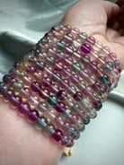 Stacked rainbow fluorite bracelets displaying natural color variation in purple, green, and clear fluorite crystals
