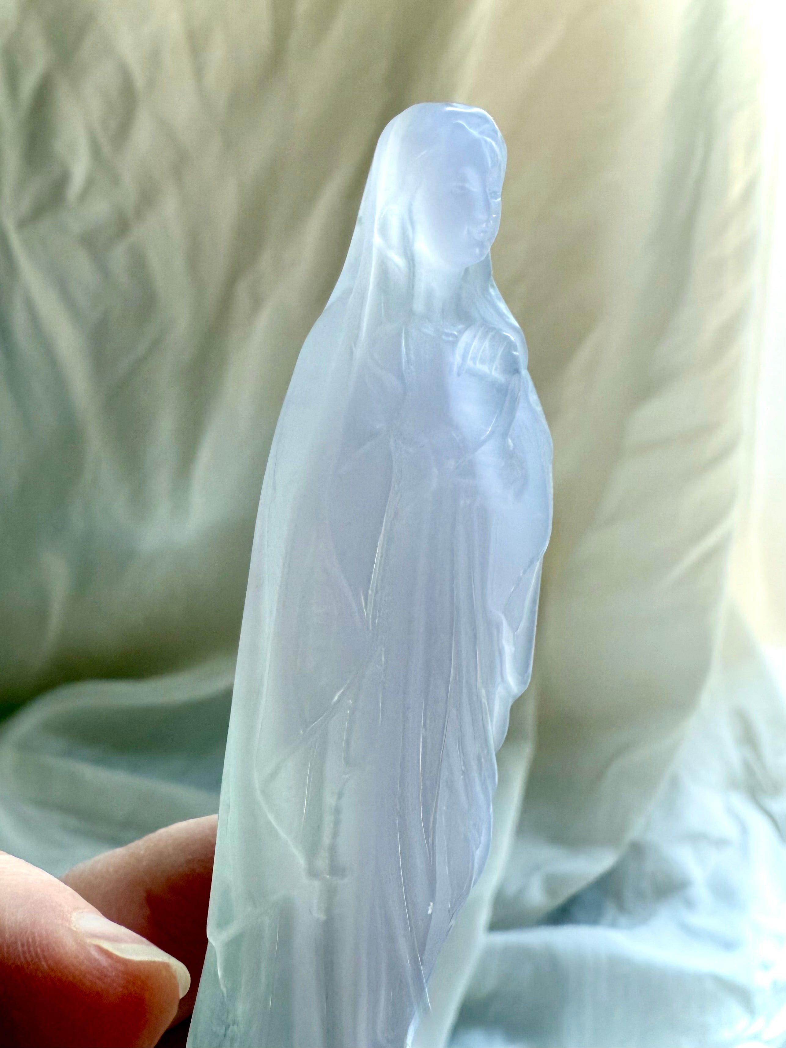 Mother Mary crystal statue in pale Lavender Fluorite, held in hand to show the carving’s size and delicate details