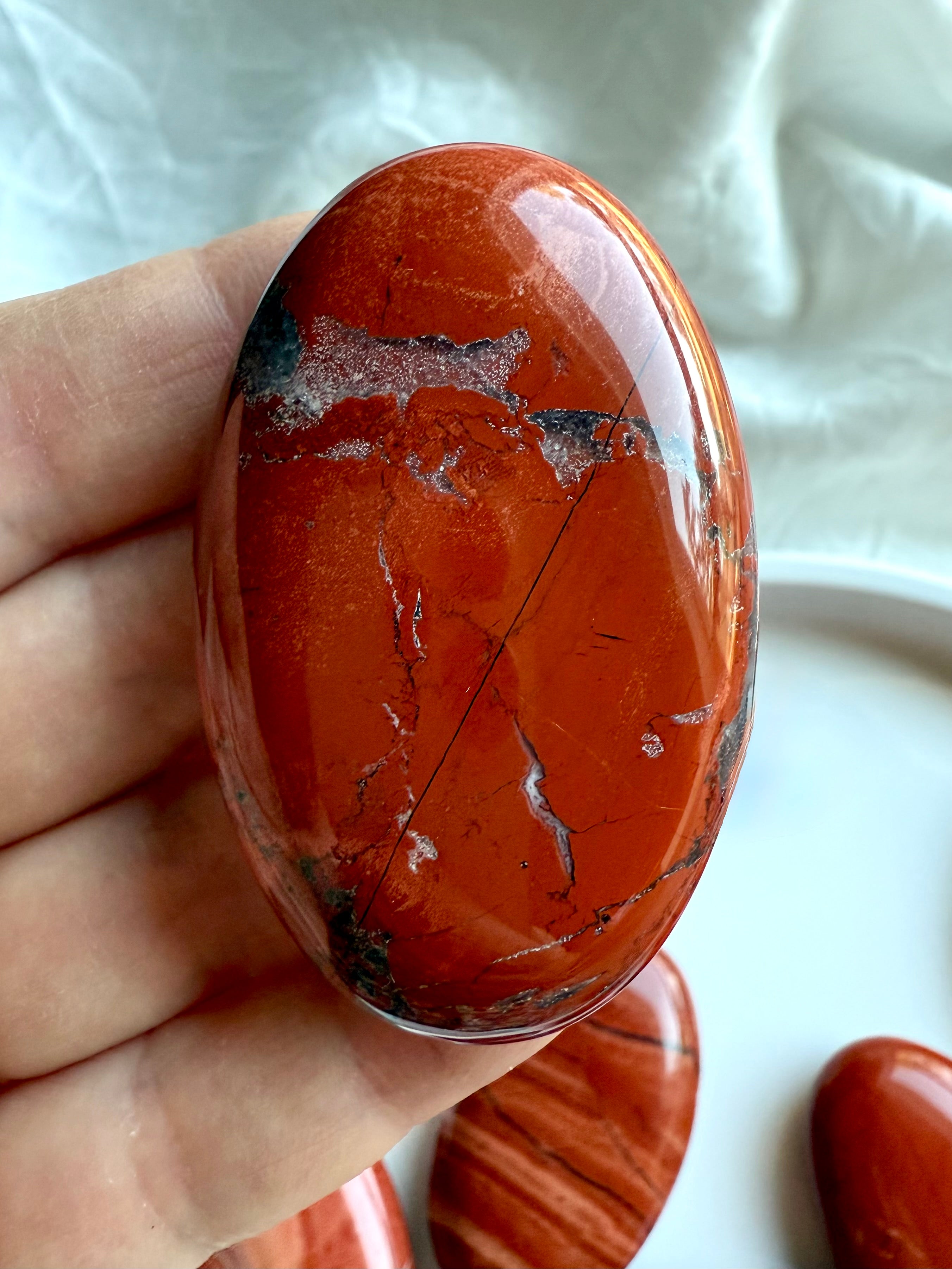 Detailed view of Red Jasper palm stone — earthy red crystal with natural patterns and inclusions.