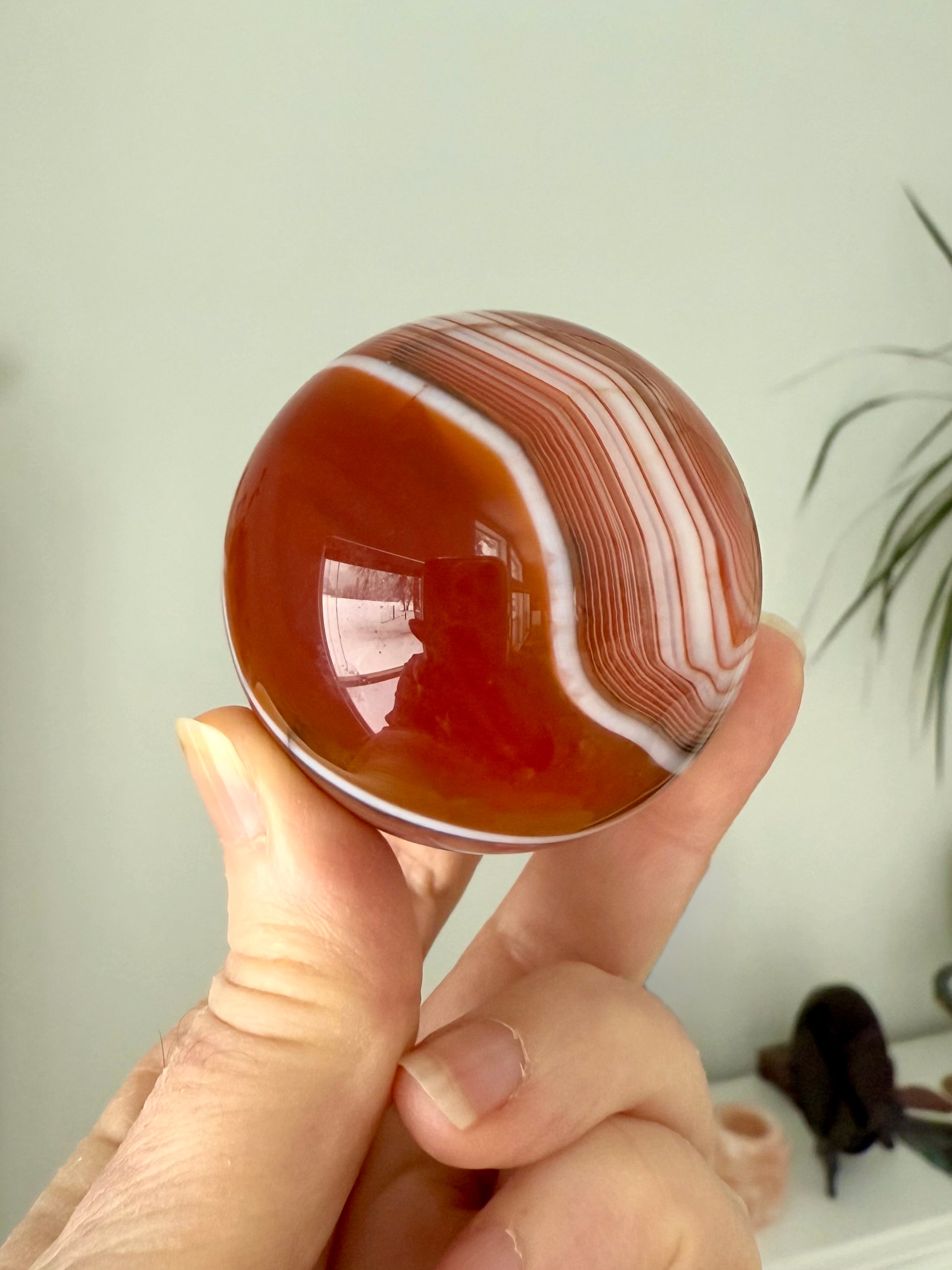 A banded carnelian crystal ball with an intricate chevron pattern swirling around the sphere